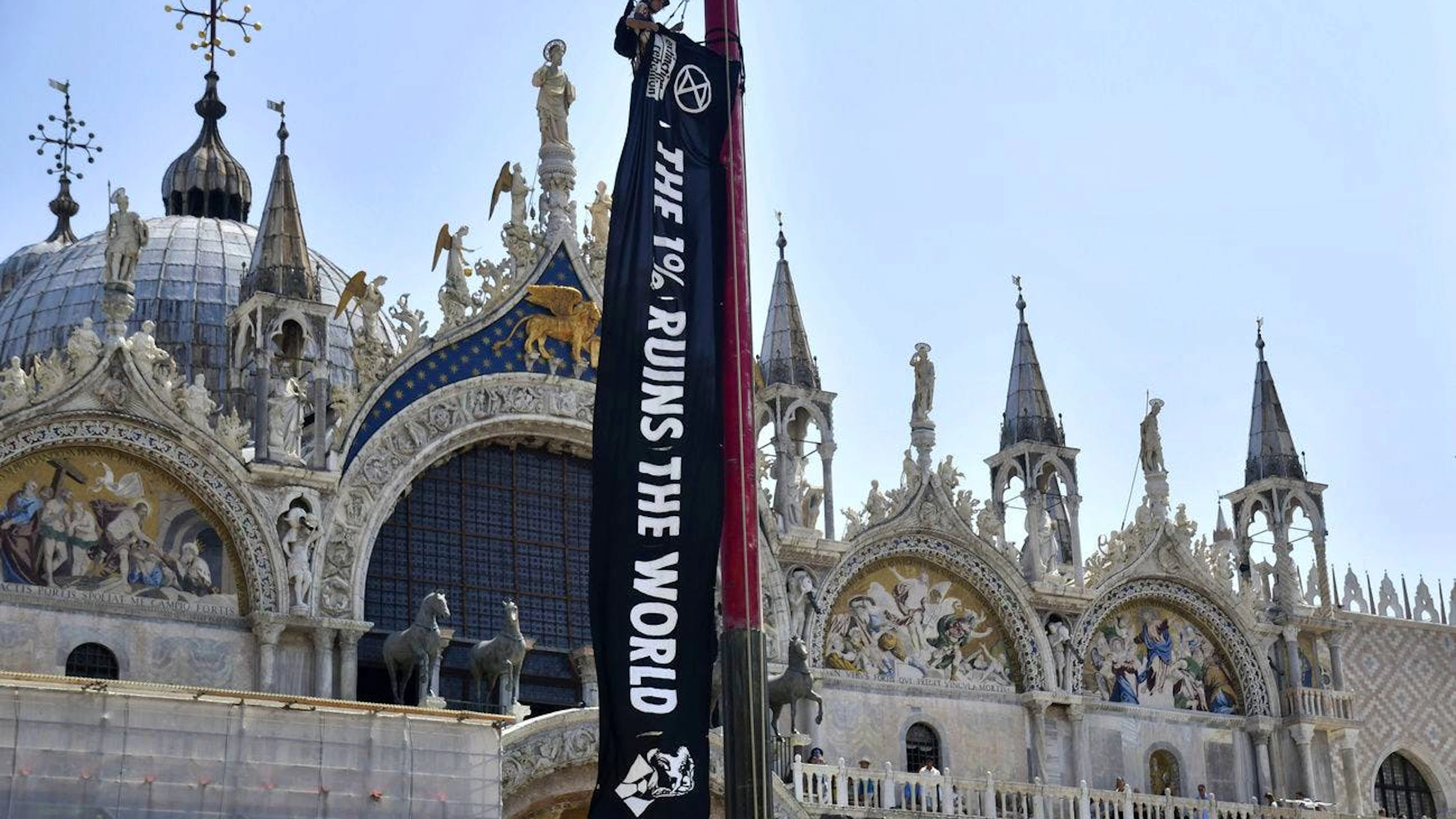 Ein Aktivist der Umweltschutzbewegung Extinction Rebellion hängt vor dem Markusdom ein Banner auf.