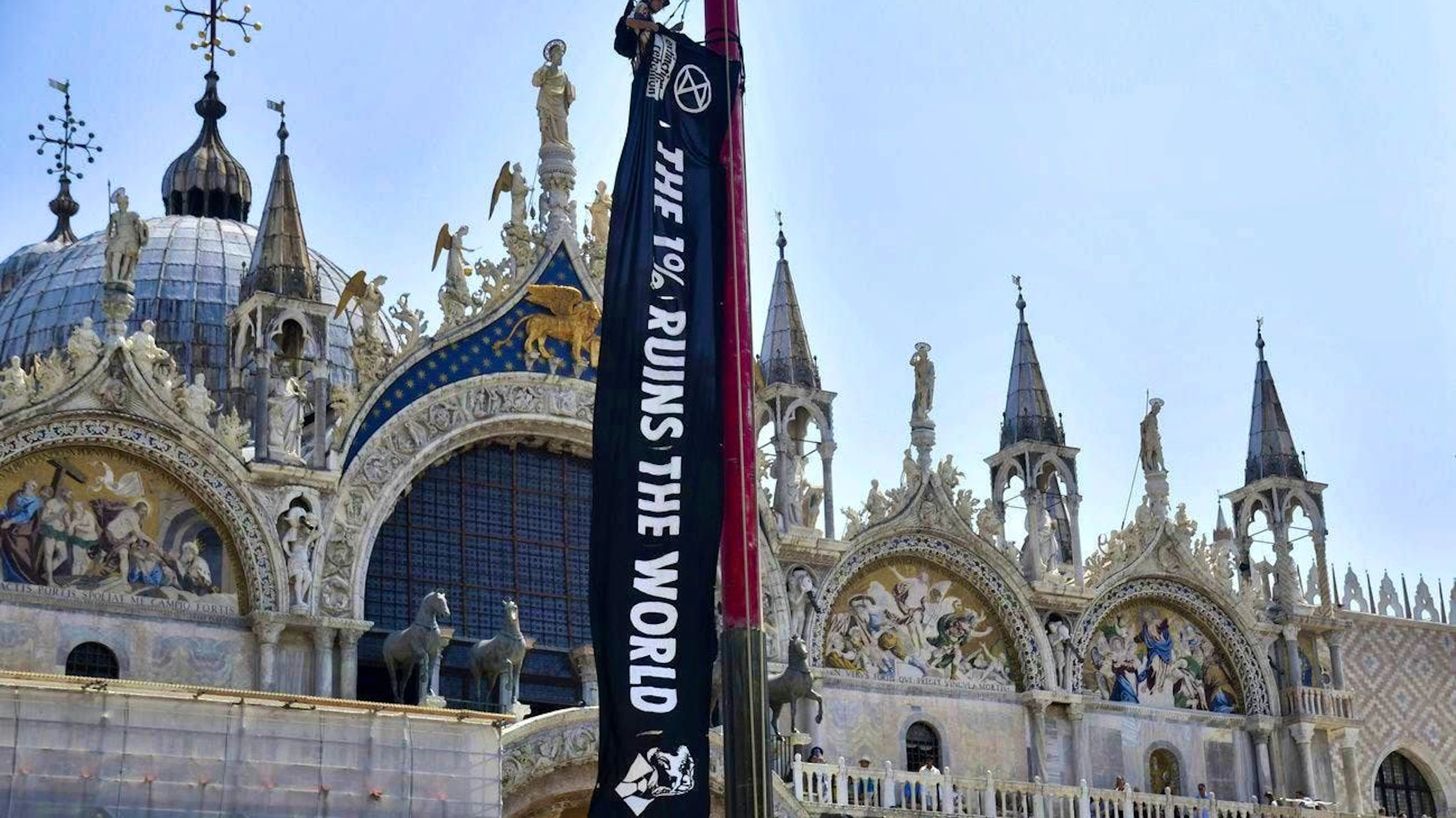 An activist from the environmental movement Extinction Rebellion hangs a banner in front of St. Mark's Basilica.