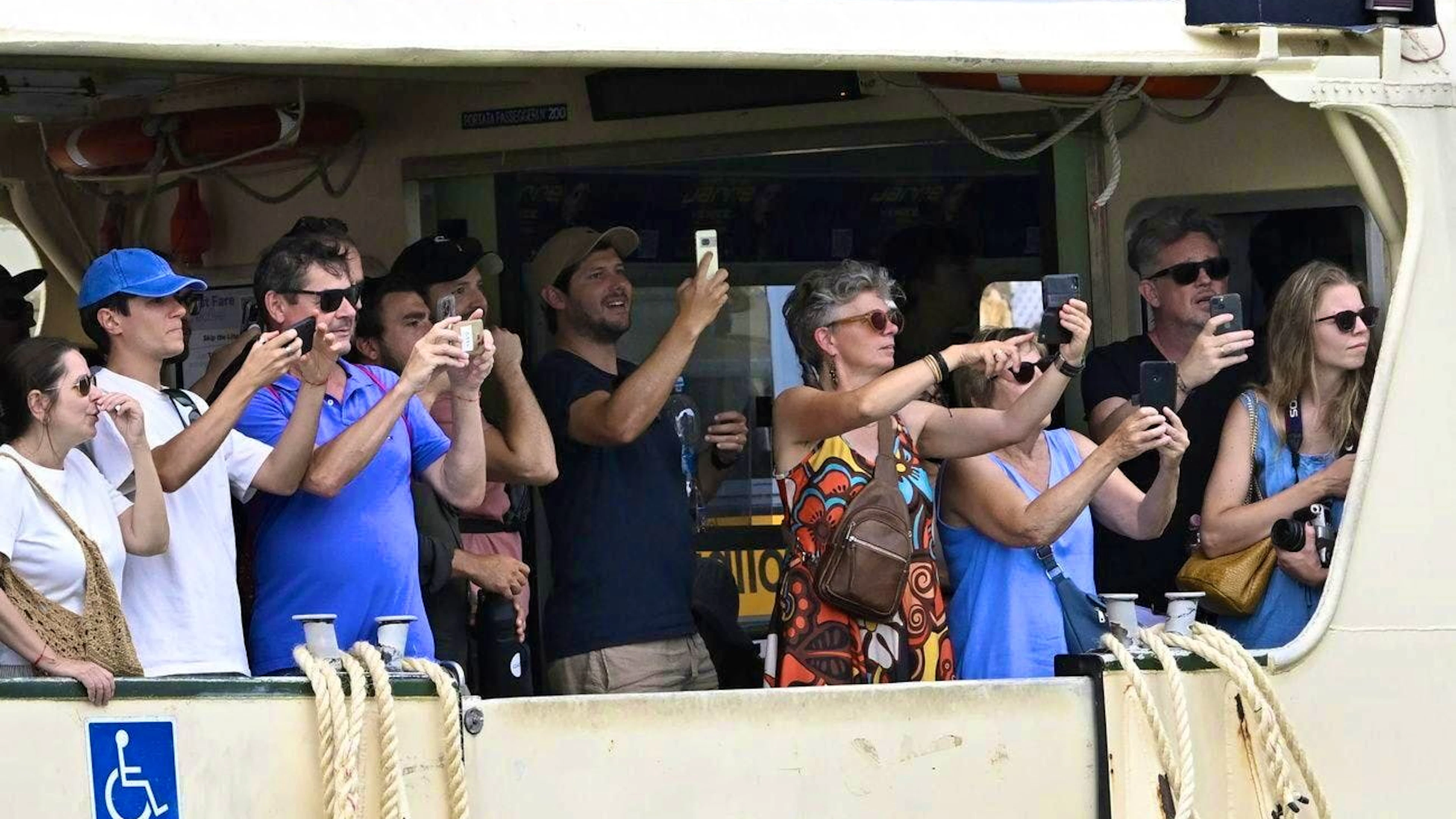 The wedding is a spectacle for tourists: passengers on a ferry watch the wedding guests.
