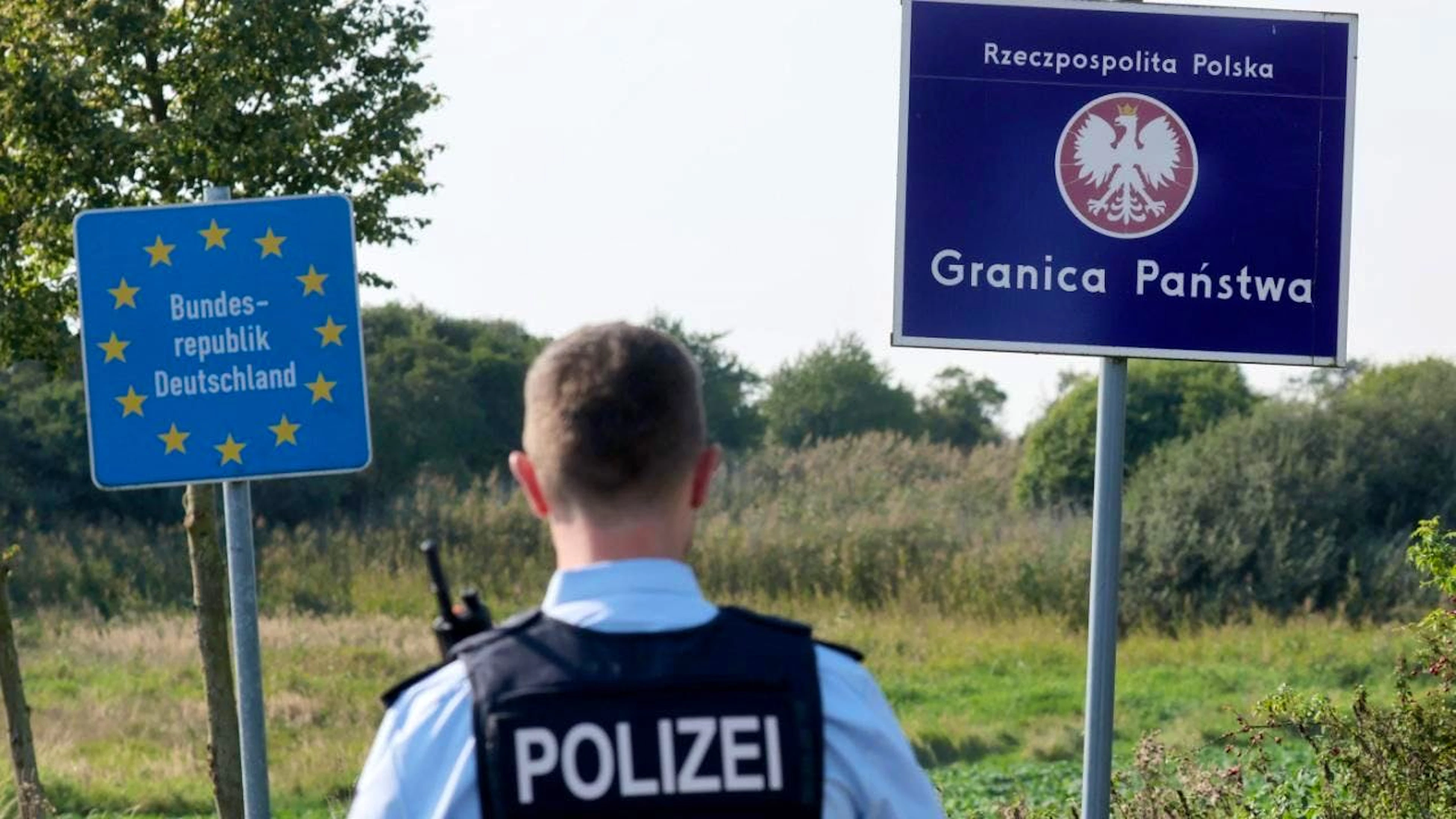 ARCHIV - Bei einer flexiblen Schwerpunktkontrolle unmittelbar an der deutsch-polnischen Grenze in der Nähe des ehemaligen Grenzübergang Linken steht ein Bundespolizist vor den Schildern für Deutschland und Polen. Laut dem Innenminister Christian Pegel zeigen Grenzkontrollen in Mecklenburg-Vorpommern Wirkung. Foto: Bernd Wüstneck/dpa
