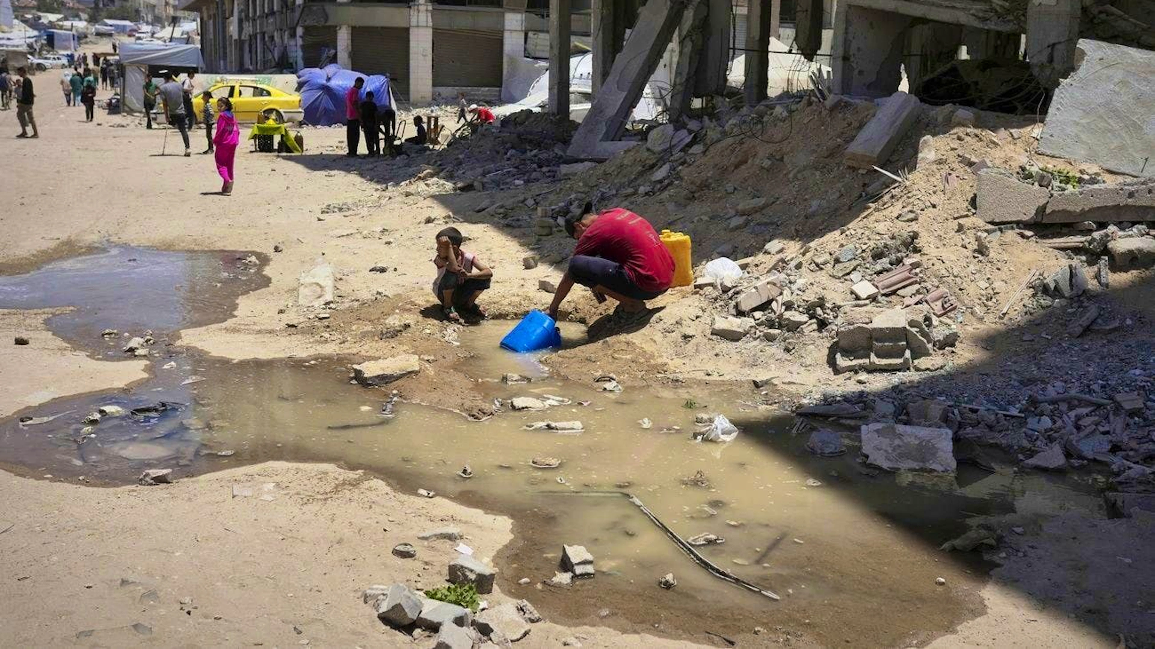 Children draw water from a puddle according to a pipe book in Gaza City on May 24.