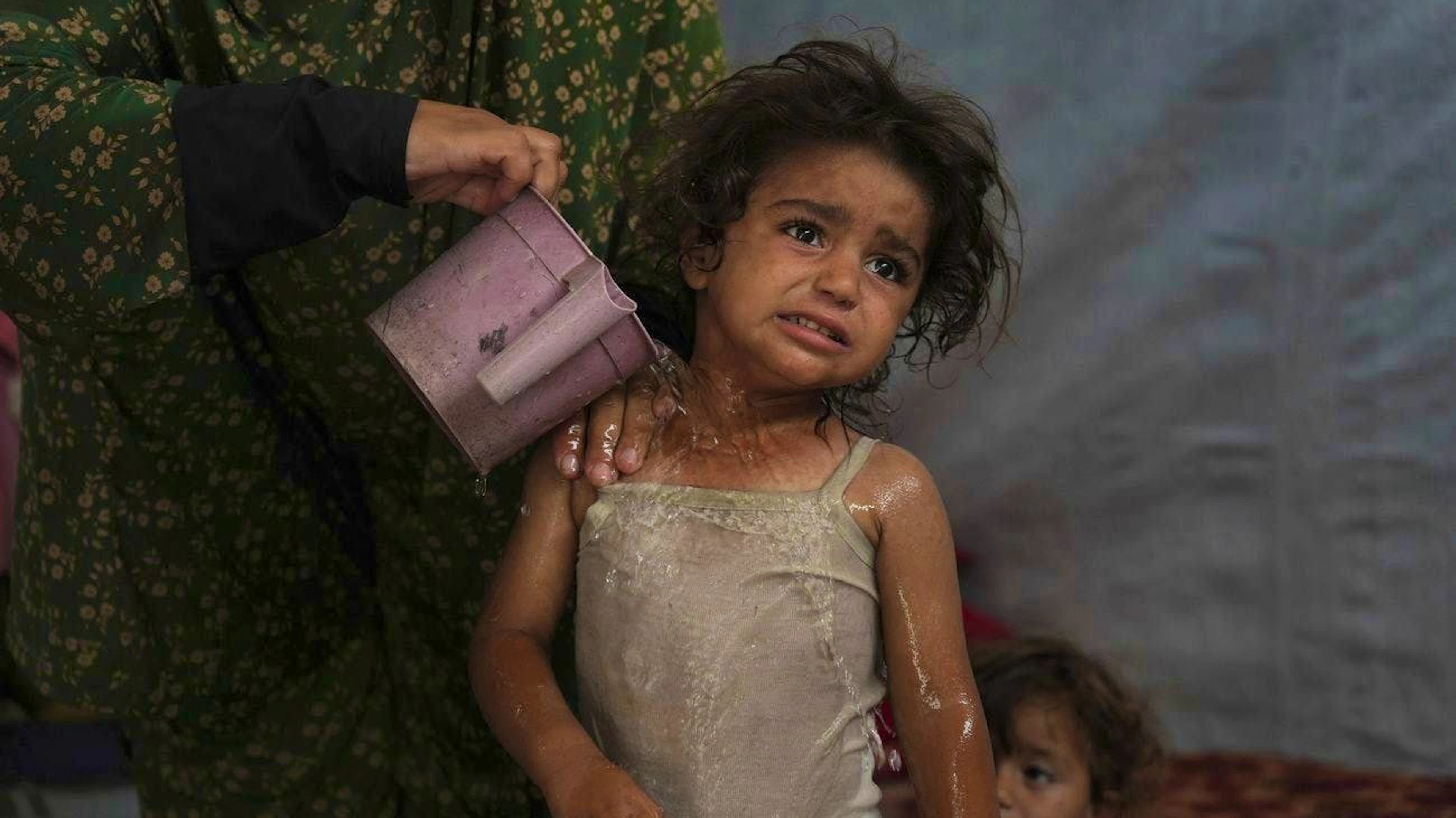Rida Abu Hadajed tries to cool her two-year-old daughter Azhar in Chan Junis on July 1.