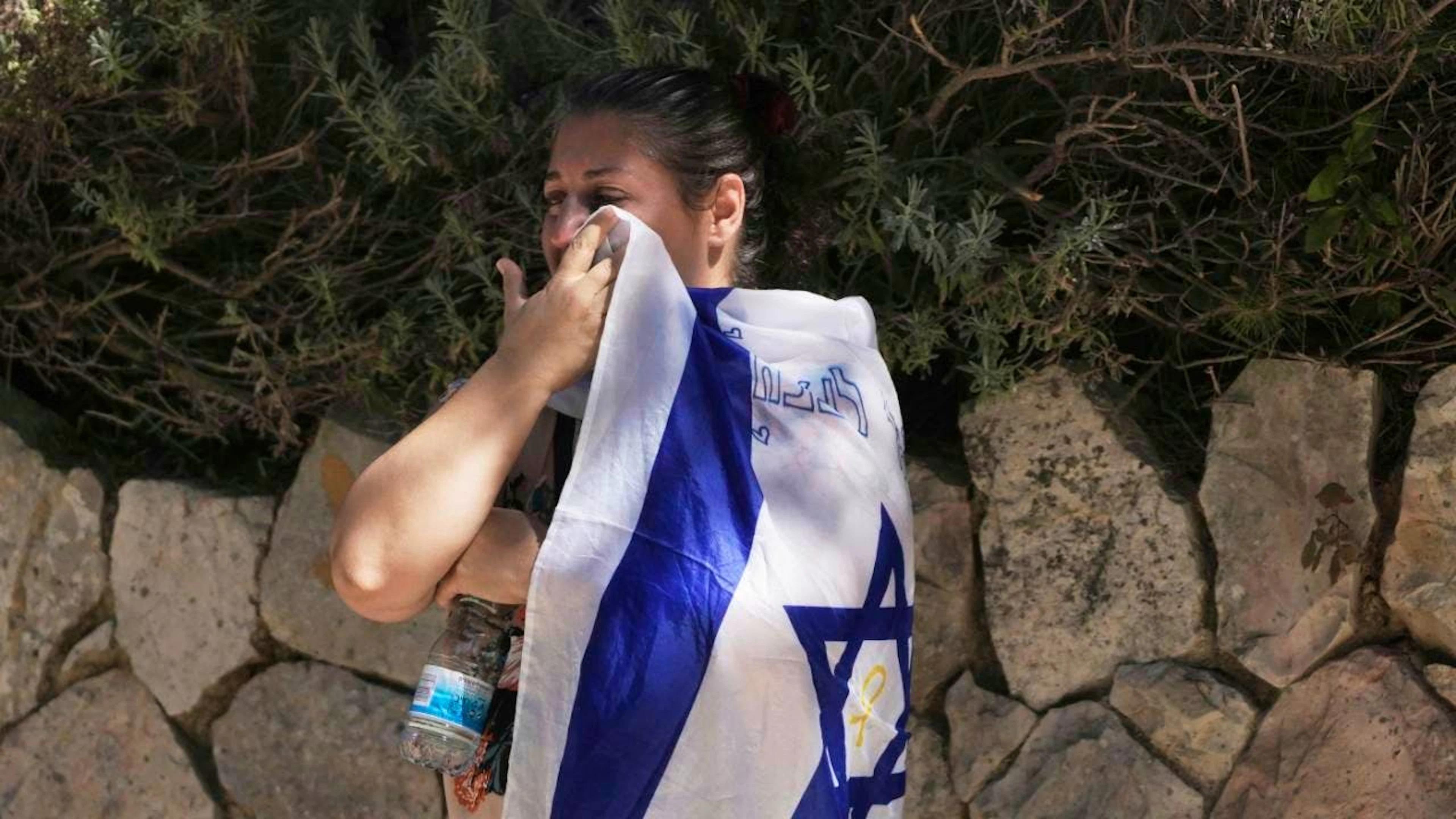 Eine Trauernde wischt ihre Tränen mit der israelischen Nationalflagge bei der Beerdigung von Noam Aharon Musgadian, Stabsfeldwebel der israelischen Streitkräfte, der im Gazastreifen gefallen ist, auf dem Militärfriedhof Mount Herzl in Jerusalem. Foto: Maya Alleruzzo/AP/dpa