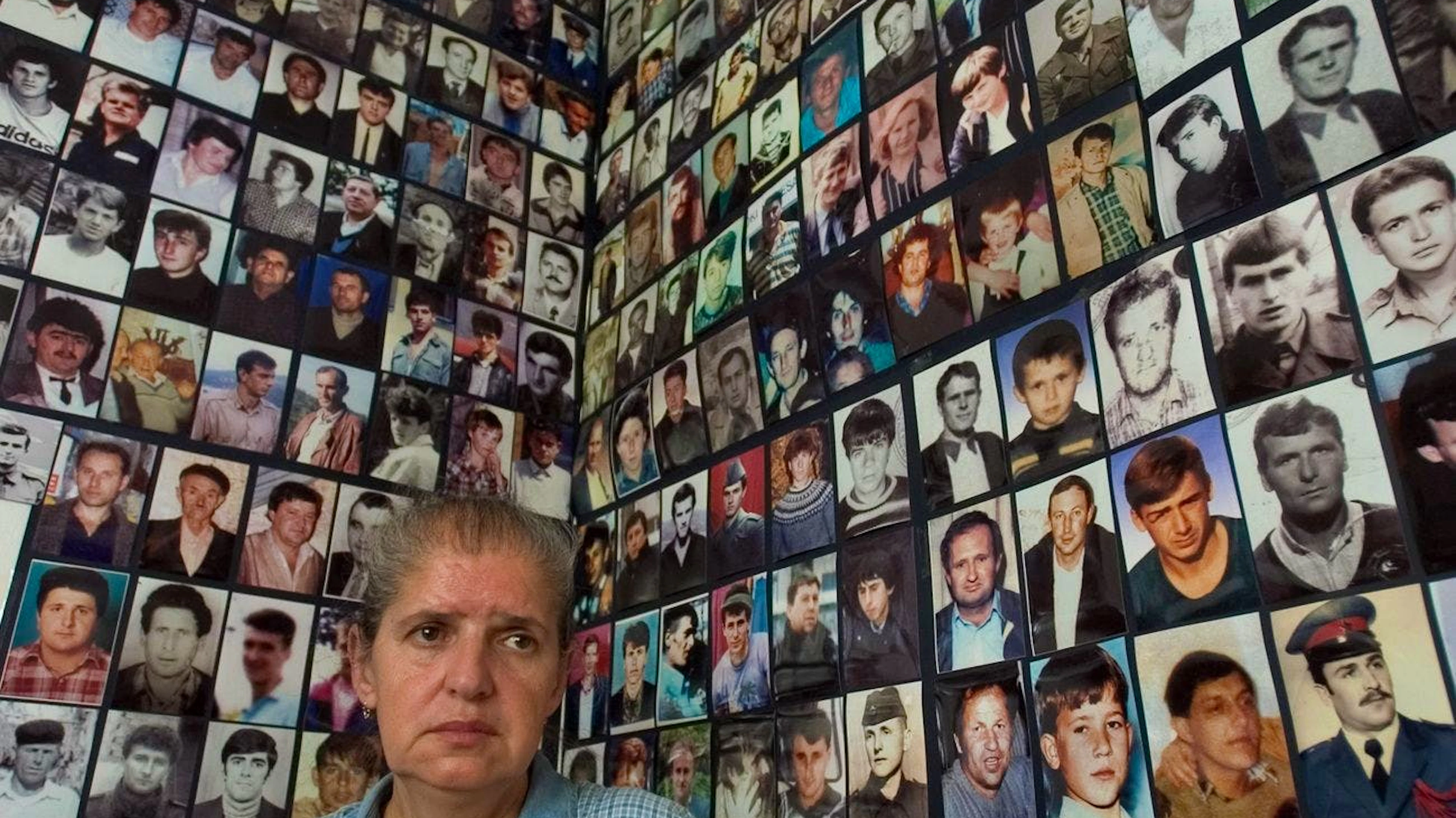 Hajra Catic, survivante du massacre de Srebrenica, se tient à côté de dizaines de photos de citoyens disparus de Srebrenica, après que l'enclave sécurisée par l'ONU soit tombée aux mains des Serbes de Bosnie en juillet 1995, à l'Association des veuves de Srebrenica à Tuzla, le mercredi 29 juin 2005.