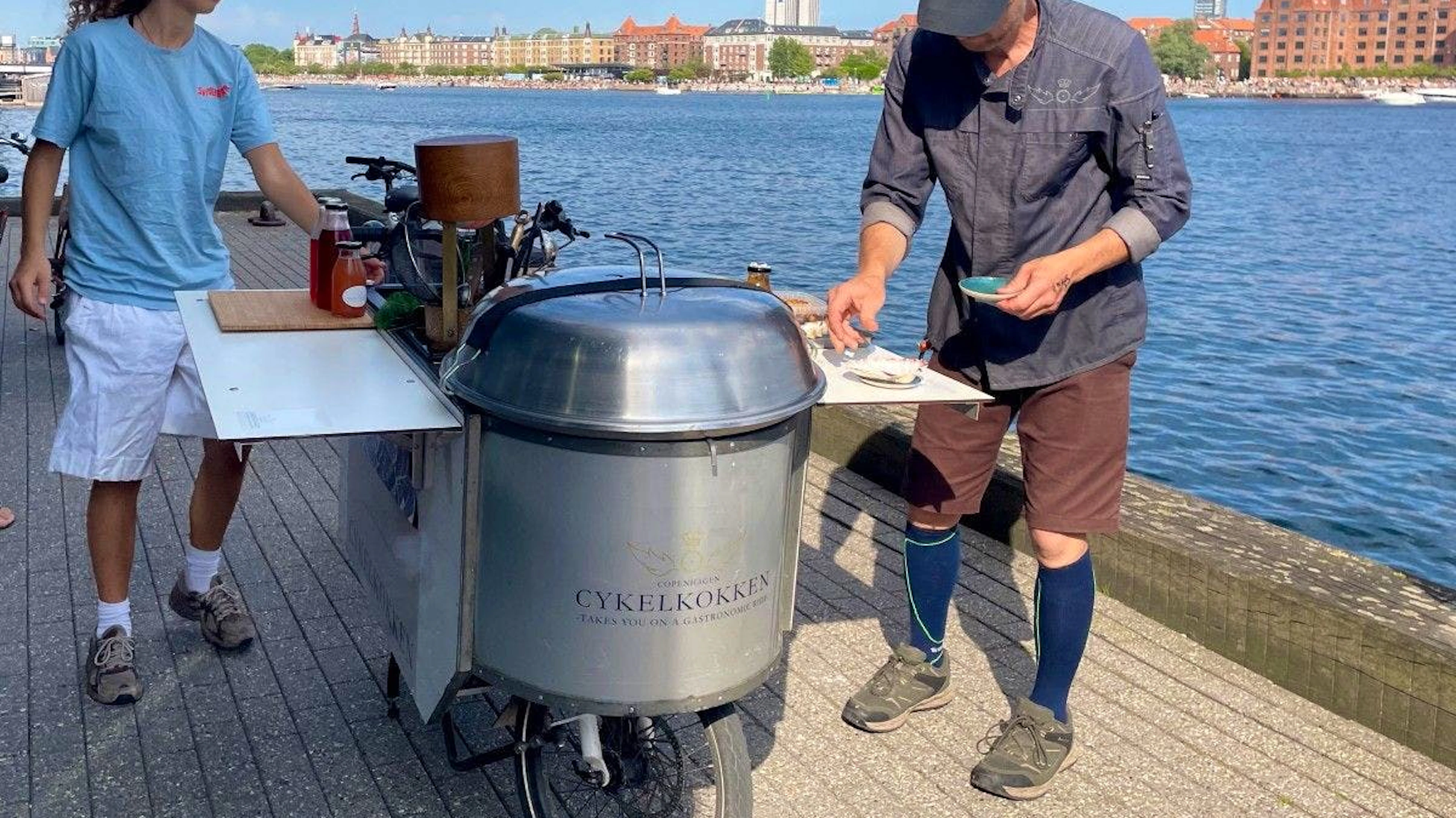 Le chef danois Morten Kryger Wulff cuisine sur son vélo-cuisine qu’il a lui-même conçu, lors d’un arrêt d’une balade gastronomique à vélo, le 2 juillet 2025 à Copenhague, au Danemark.