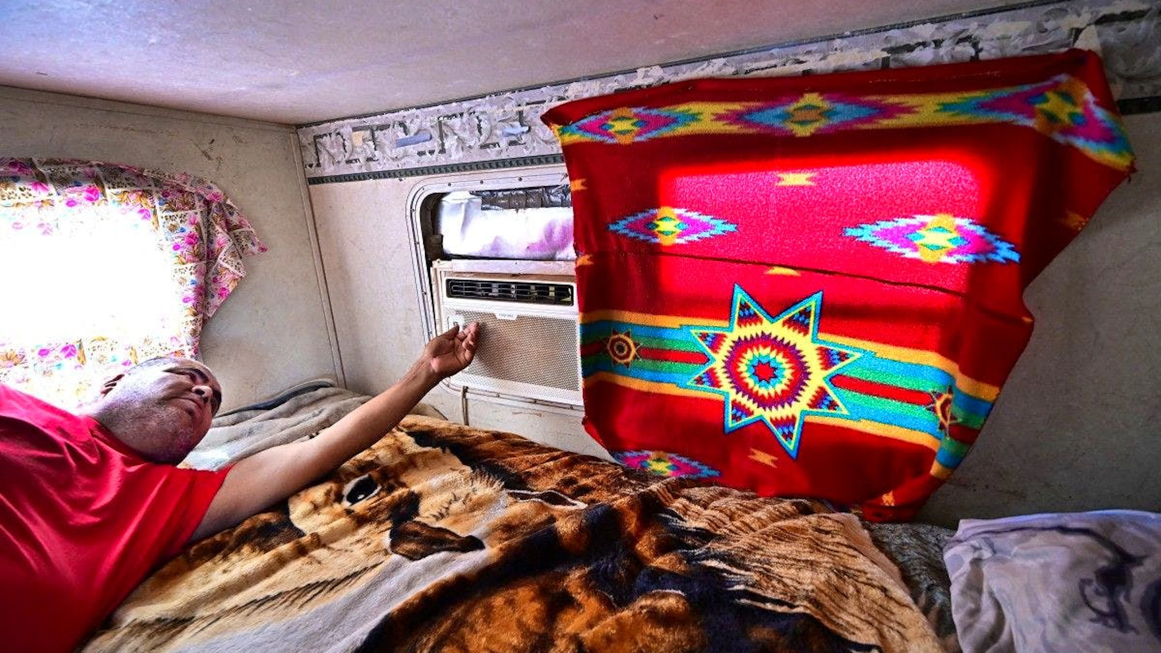 Elbert Yazzie, 54 ans, habitant de la Nation Navajo, allume son climatiseur récemment installé dans sa petite maison après avoir été raccordé au réseau électrique, le 8 juillet 2025 à Tuba City.