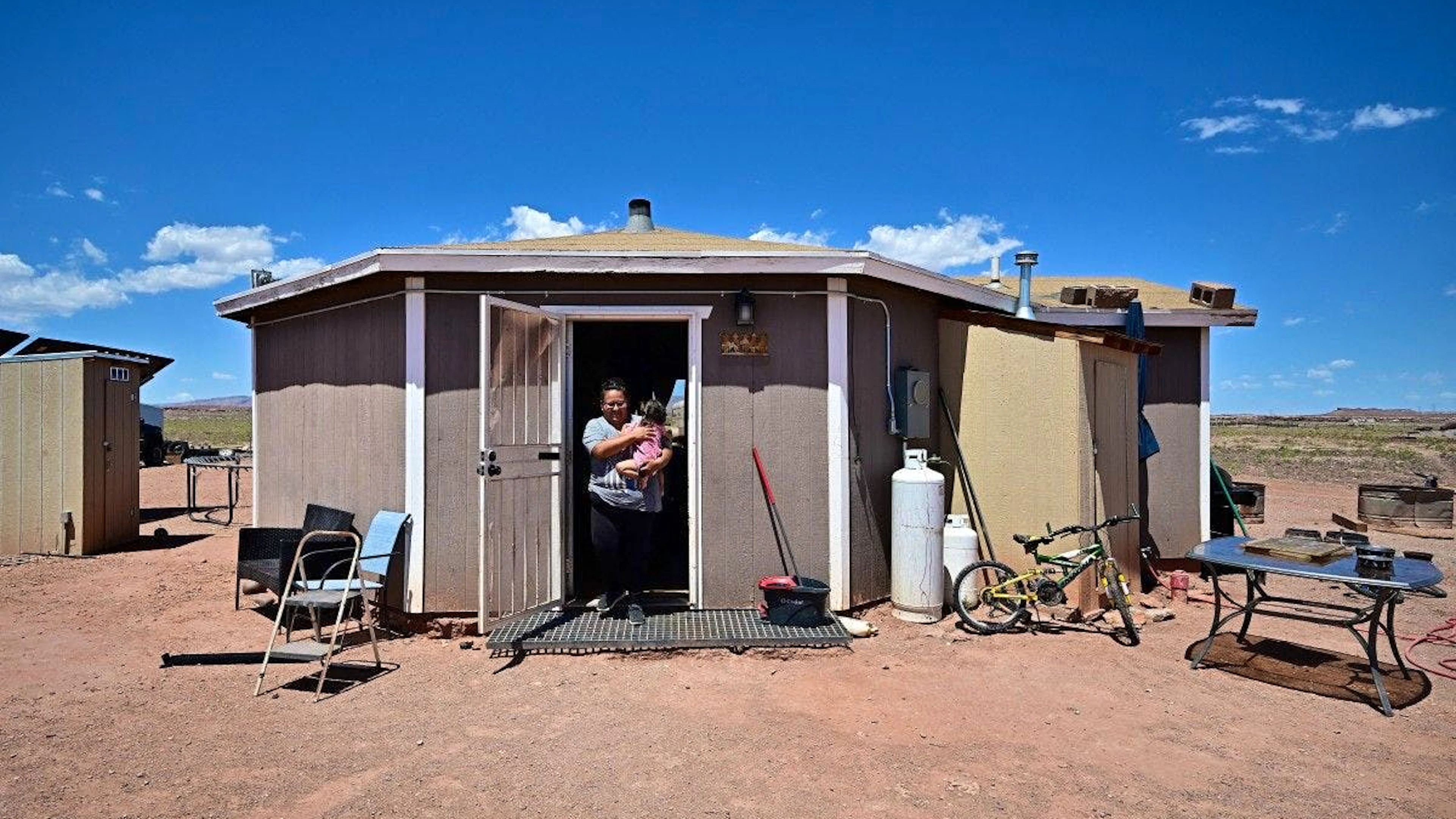 Gilberta Cortes, 42 ans, habitante de la Nation Navajo, porte son enfant devant leur maison à Cameron, en Arizona, le 9 juillet 2025.