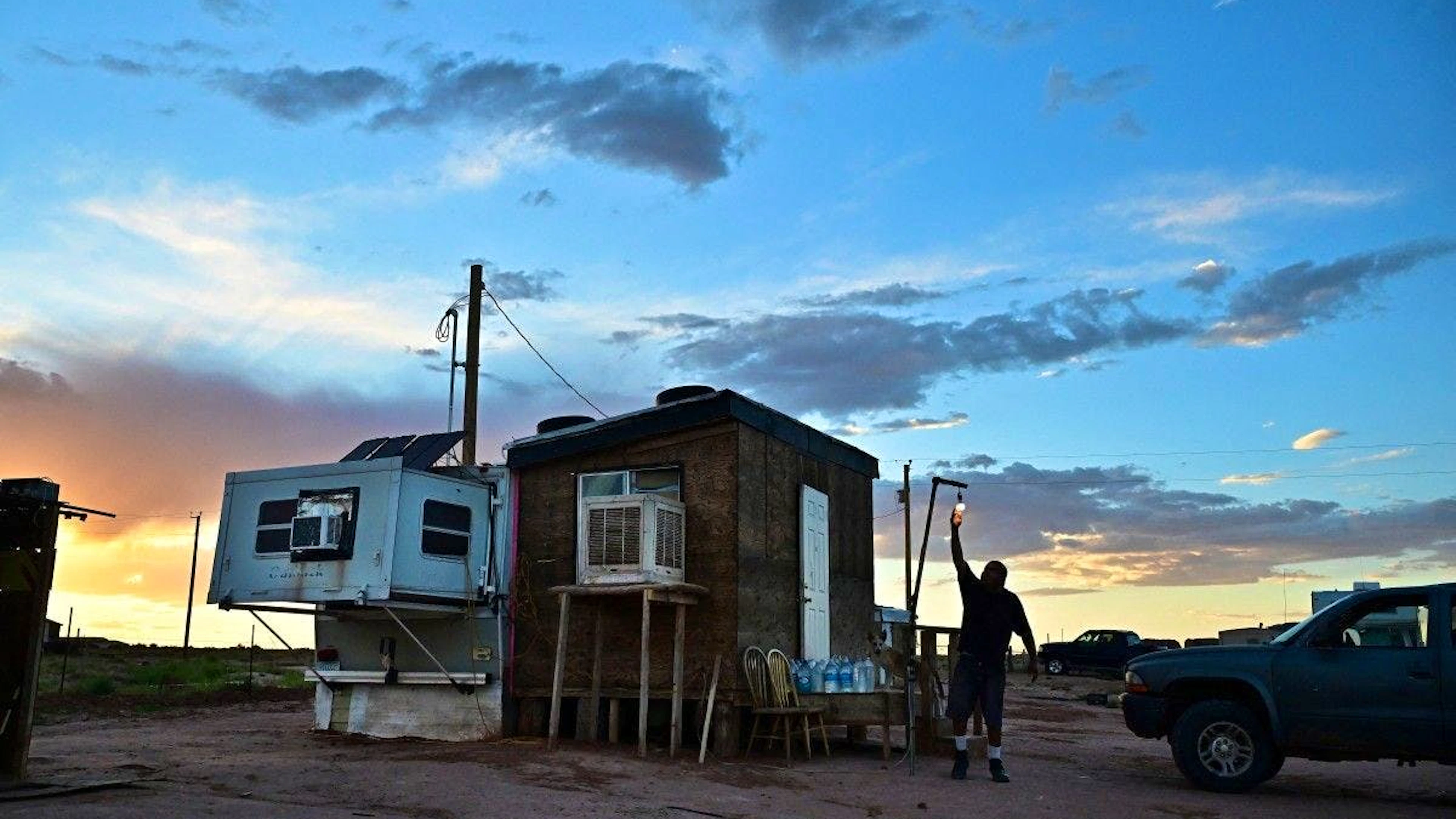 Elbert Yazzie, 54 ans, habitant de la Nation Navajo, ajuste une ampoule devant sa petite maison après avoir récemment été raccordé au réseau électrique, le 8 juillet 2025 à Tuba City, en Arizona.