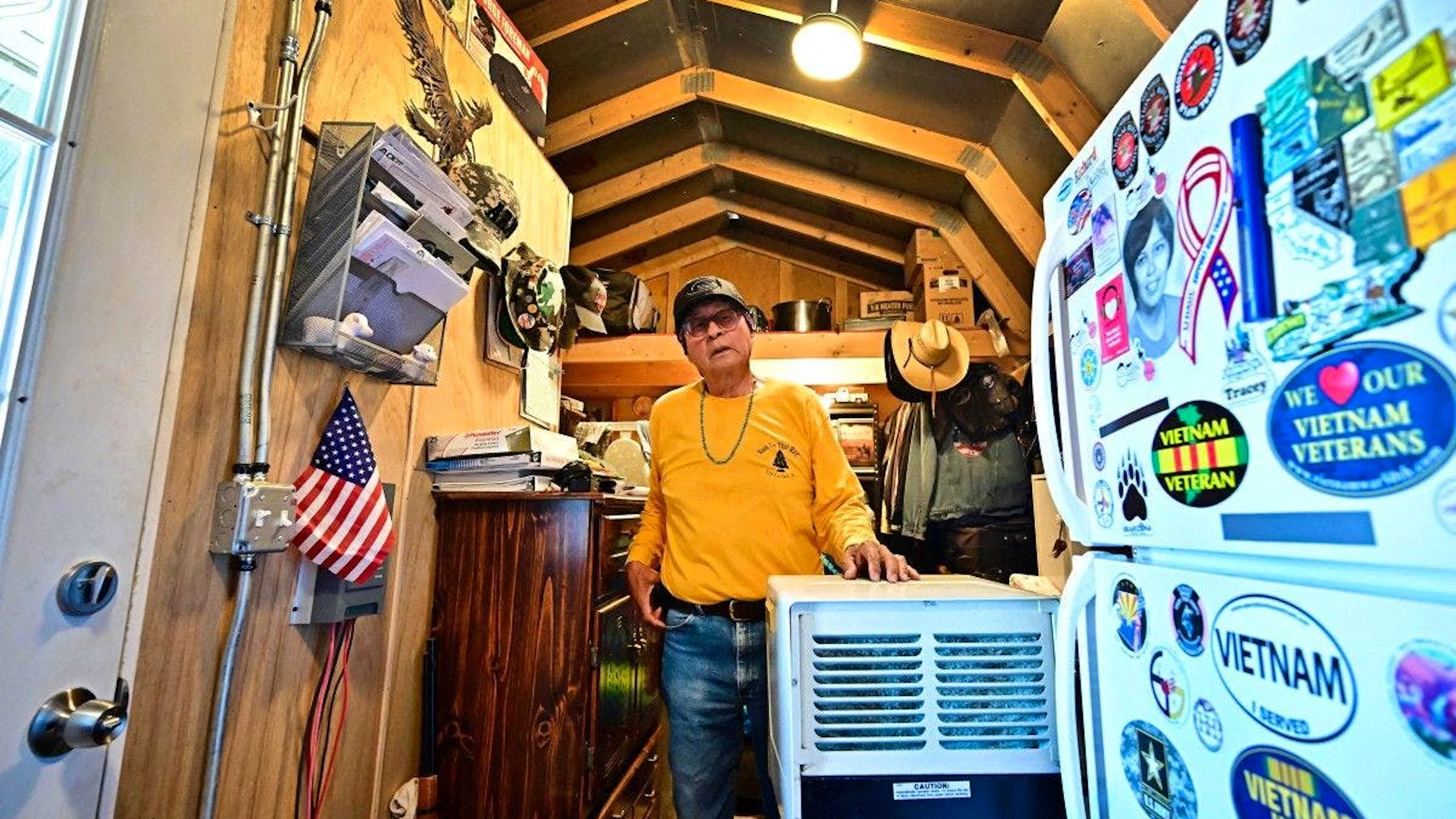 Will, vétéran de l’armée américaine et habitant de la Nation Navajo, se tient à côté d’un climatiseur alimenté par un générateur dans sa petite maison, qu’il qualifie lui-même de “cabane à outils”, à Cameron.