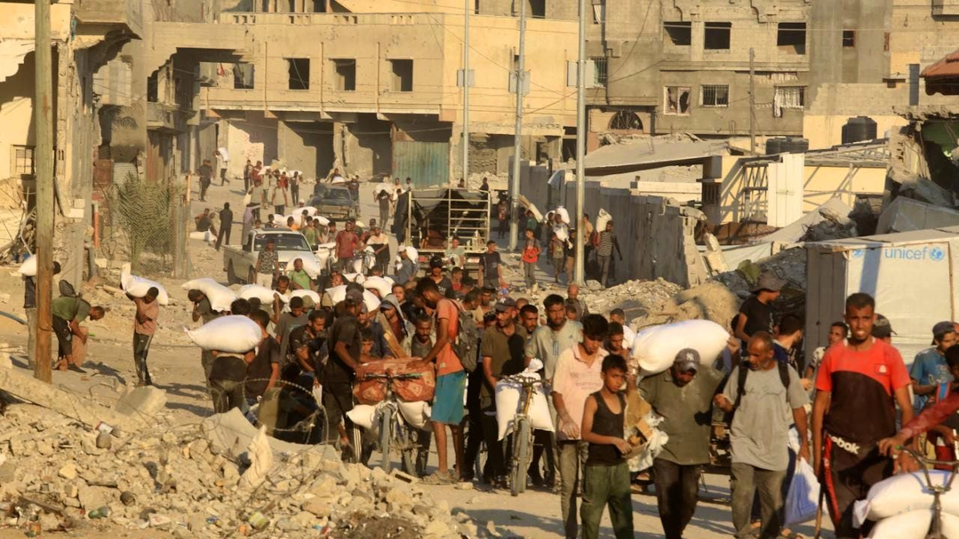Palästinenser tragen Mehlsäcke entlang einer Straße in Chan Junis, nachdem Lastwagen mit humanitärer Hilfe über den von Israel kontrollierten Grenzübergang Kerem Shalom in den südlichen Gazastreifen eingefahren sind. Foto: Abed Rahim Khatib/dpa