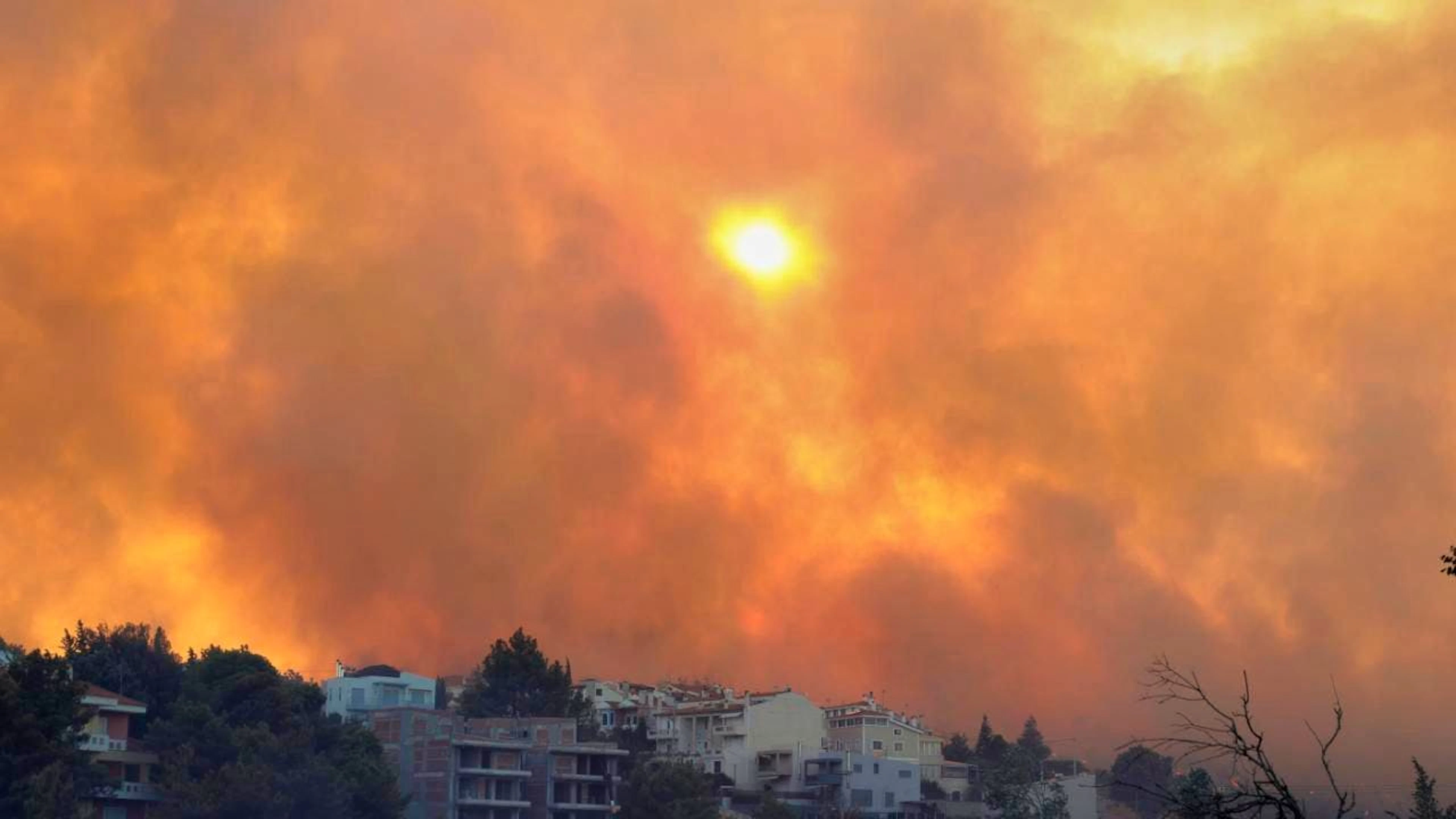 Rauch bedeckt den Himmel während eines Waldbrandes im nordwestlichen Vorort Kryoneri. Foto: Yorgos Karahalis/AP/dpa