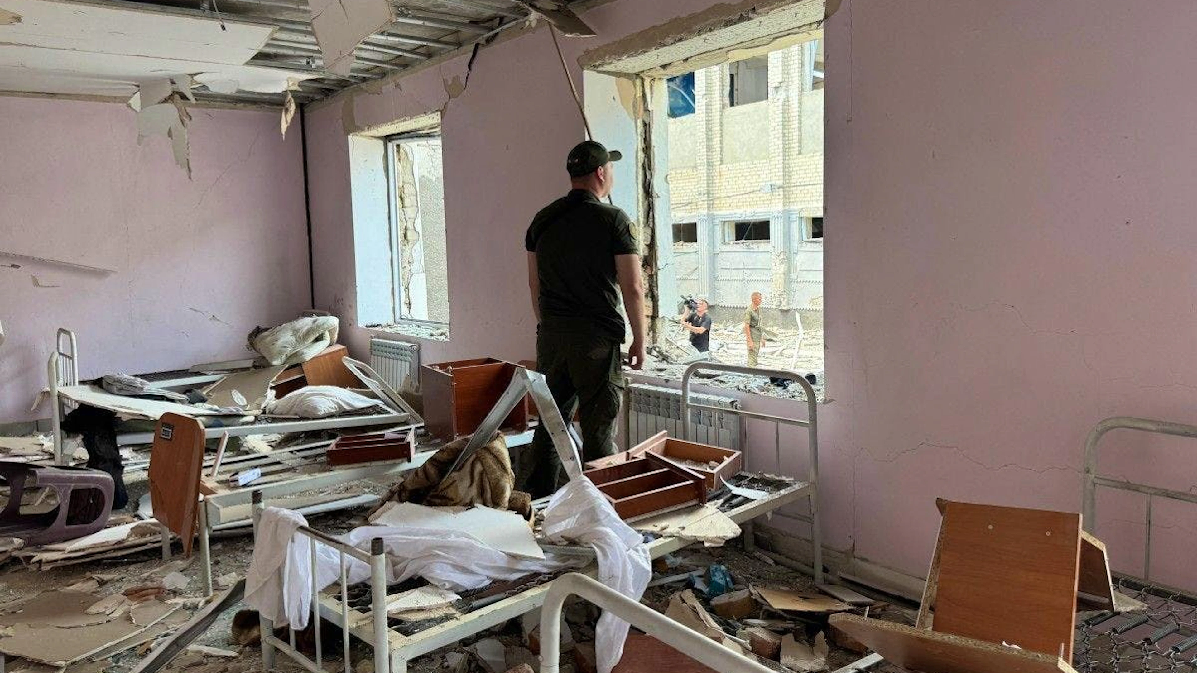Un membre des forces de l’ordre ukrainiennes regarde par une fenêtre brisée à l’intérieur d’un bâtiment détruit de la colonie pénitentiaire de Bilenkivska, à la suite d’une frappe aérienne survenue à Bilenke, dans la région de Zaporijjia, le 29 juillet 2025.