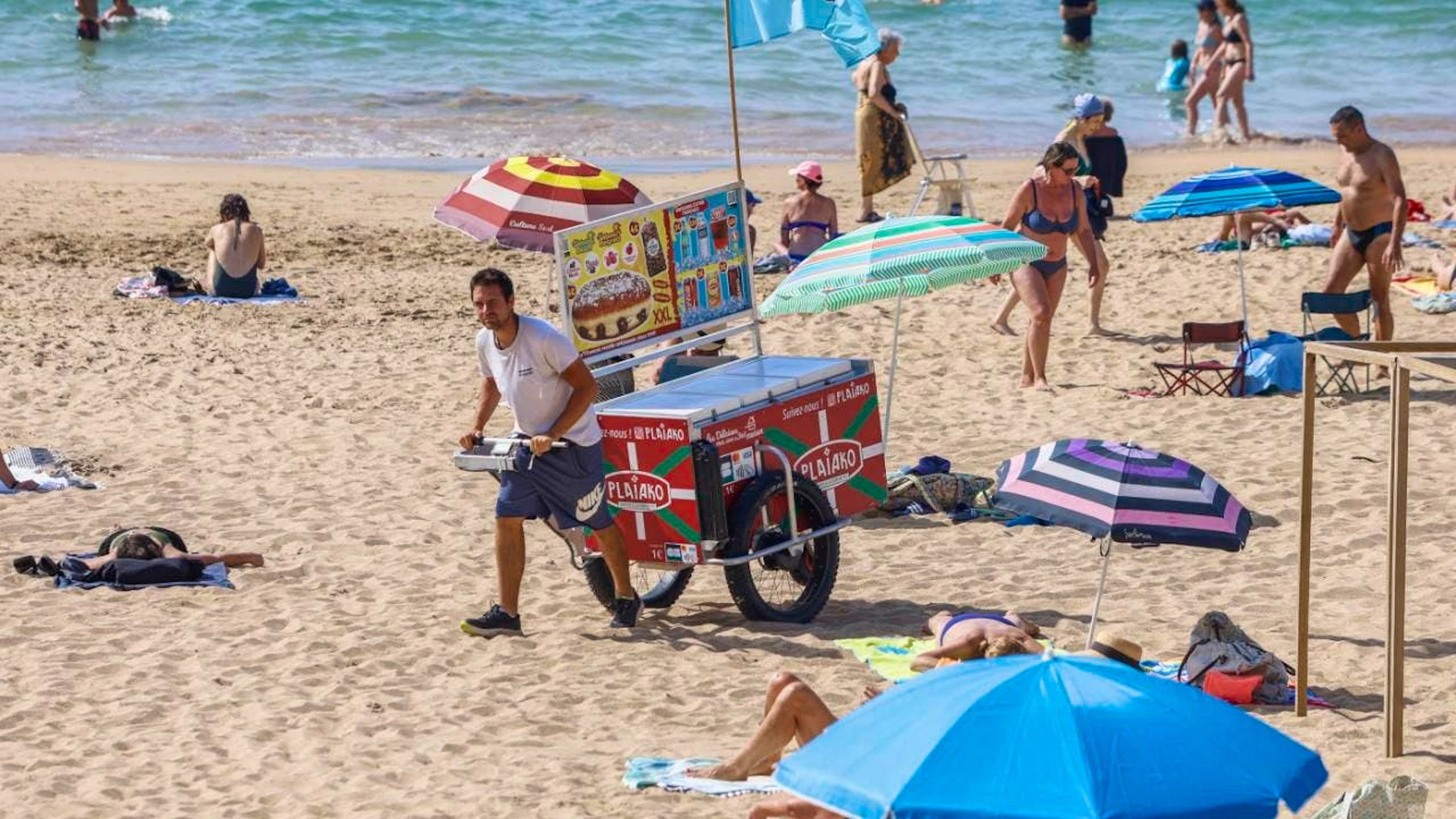 ARCHIV - Ein Strandverkäufer verkauft Eis am Strand. Der beliebte französische Badeort Les Sables- d'Olonne ermahnt Strandgäste neuerdings zu angemessener Kleidung auf seinen Straßen. Foto: Nicolas Mollo/AP/dpa