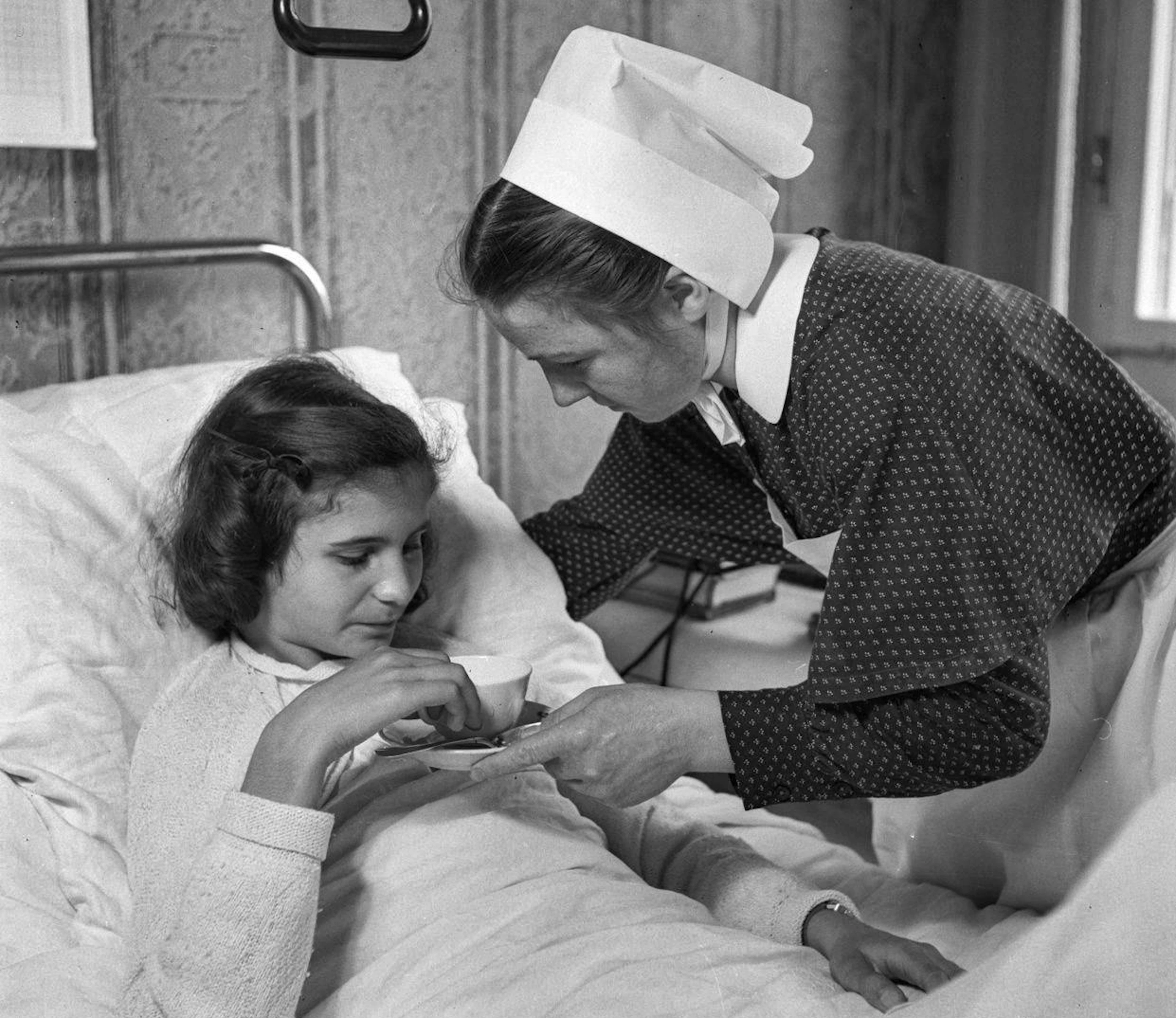 They actually have nothing to do with cashew nut allergy: a deaconess nurse at the bedside of a child, photographed in Switzerland in 1946.