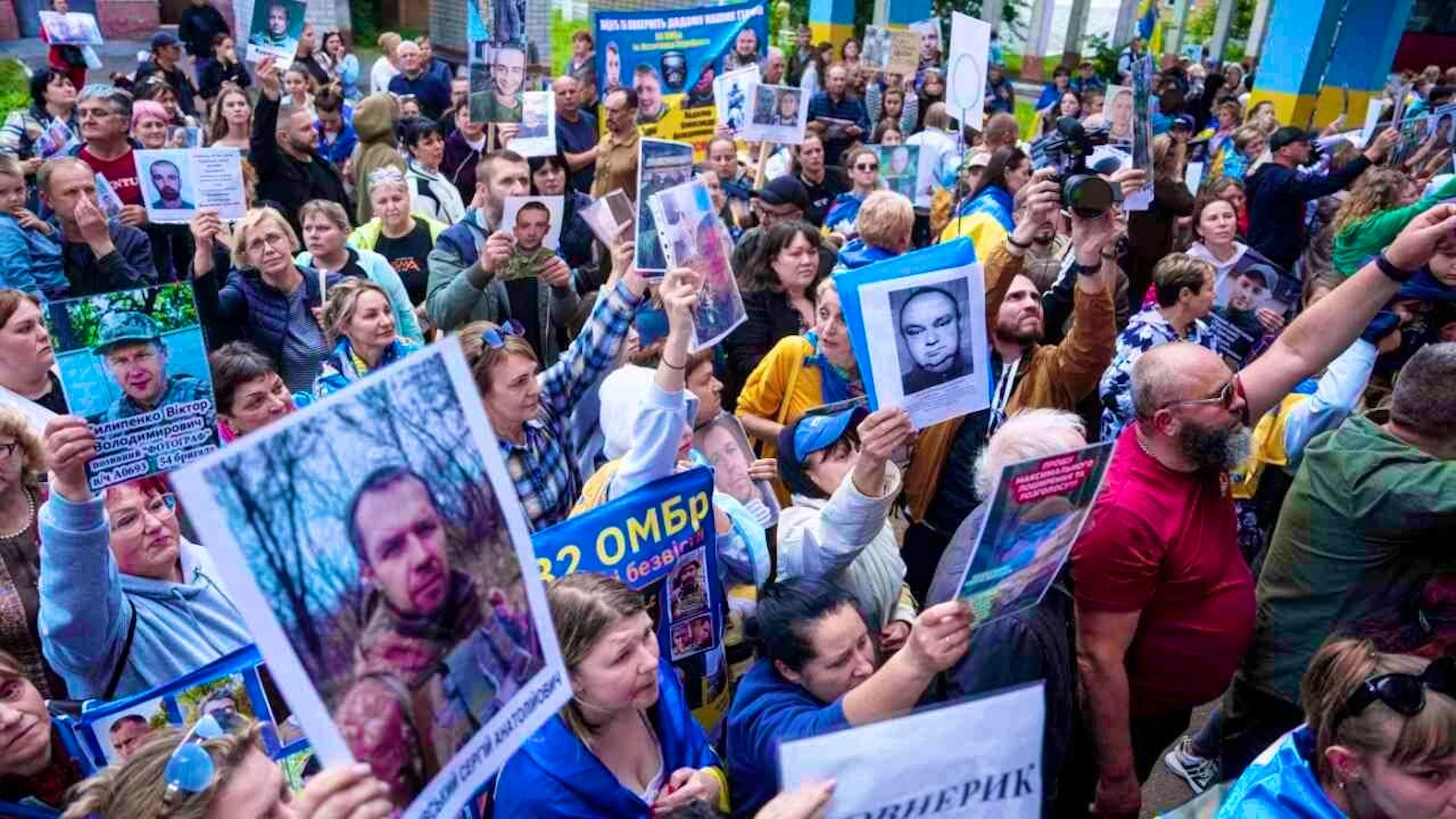 ARCHIVE - People hold photos of their missing relatives as Ukrainian soldiers return from captivity during a prisoner of war exchange between Russia and Ukraine. Photo: Evgeniy Maloletka/AP/dpa/Archive photo