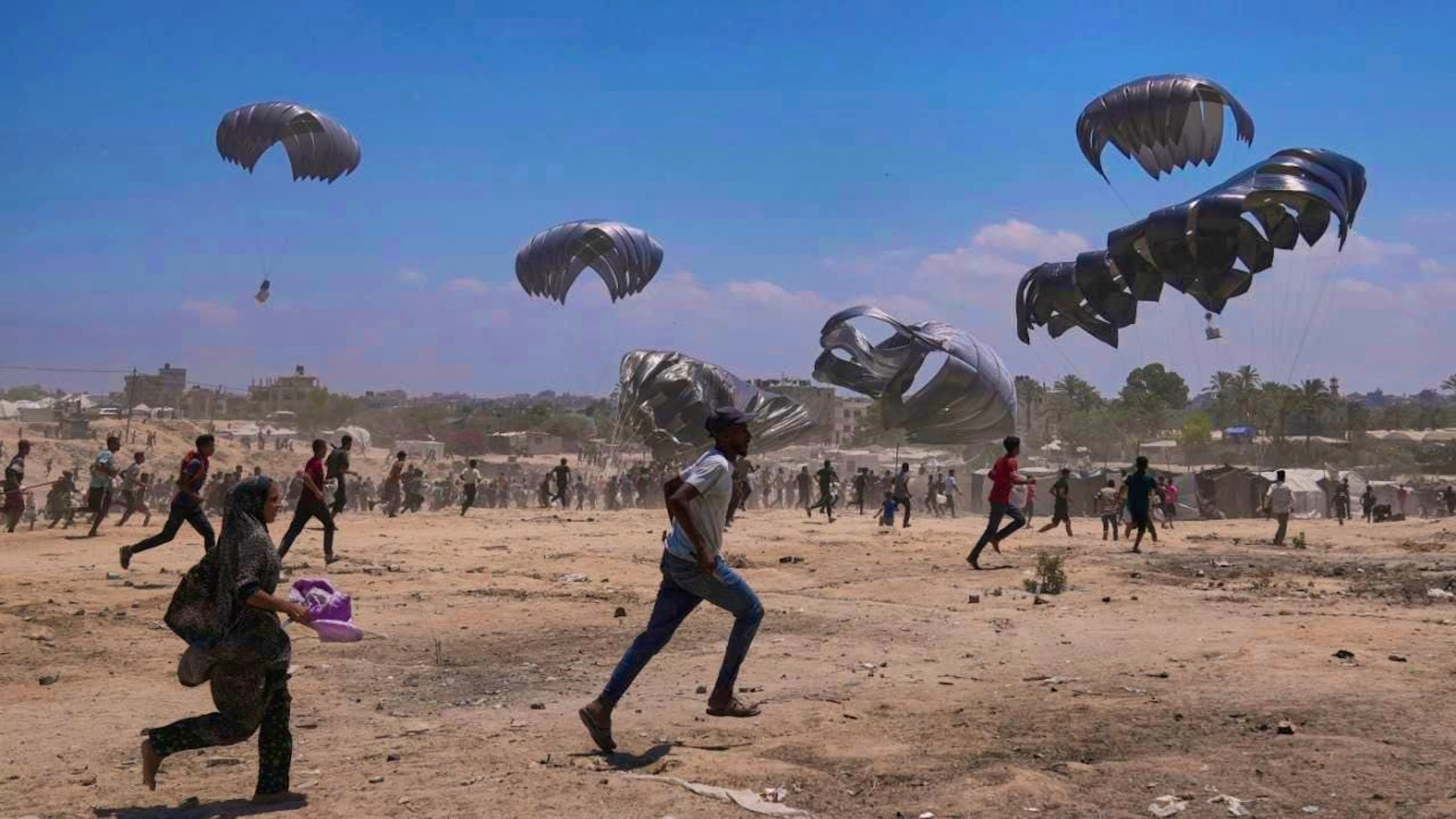Palestinians hurry to collect humanitarian aid dropped by parachute in the central Gaza Strip. Photo: Abdel Kareem Hana/AP/dpa