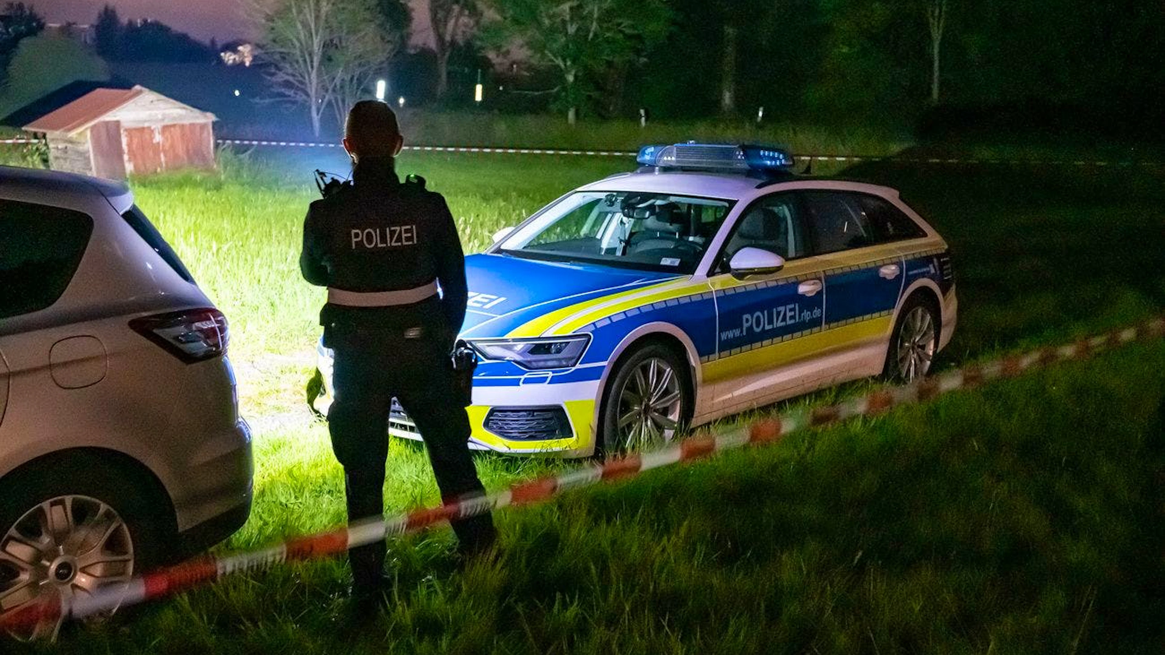 Polizeibeamte sichern am Dienstagabend in Weitefeld in Rheinland-Pfalz einen Leichenfundort ab.