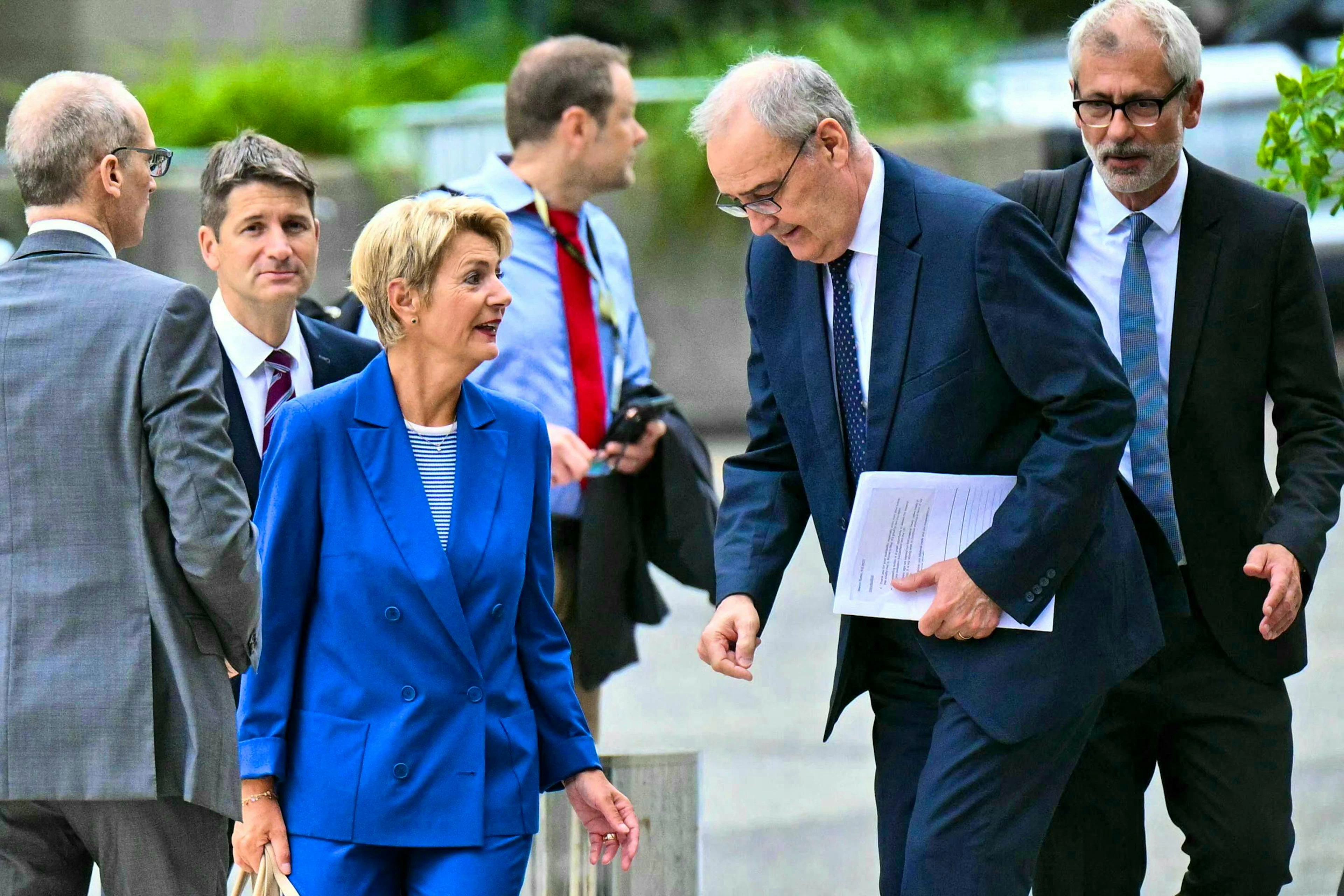 La presidente della Confederazione Karin Keller-Sutter parla con il ministro dell'Economia Guy Parmelin, che tiene in mano un dossier, al suo arrivo al Dipartimento di Stato, dove è previsto un incontro con il segretario di Stato americano Marco Rubio, a Washington il 6 agosto 2025.