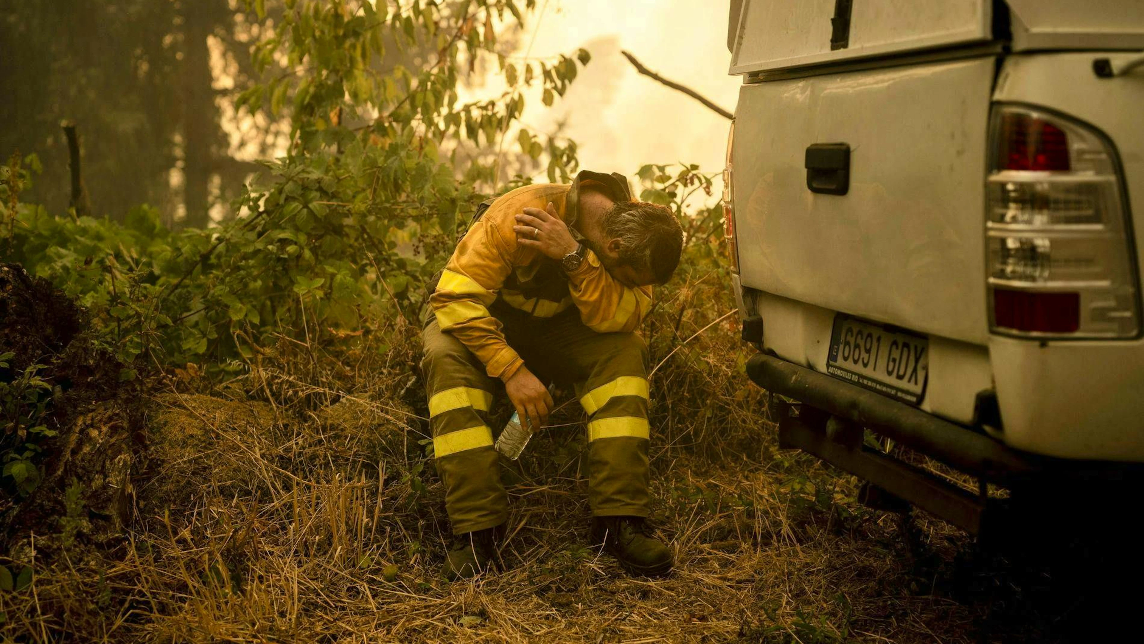 A firefighter rests while helping to extinguish a forest fire in Carballeda de Avia.