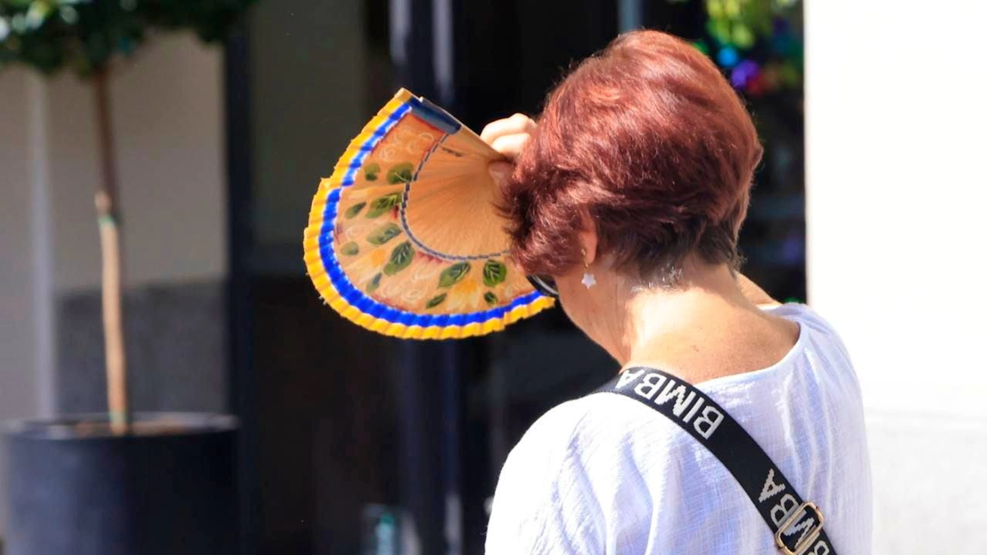 Una donna si rifugia dietro un ventaglio a Madrid.