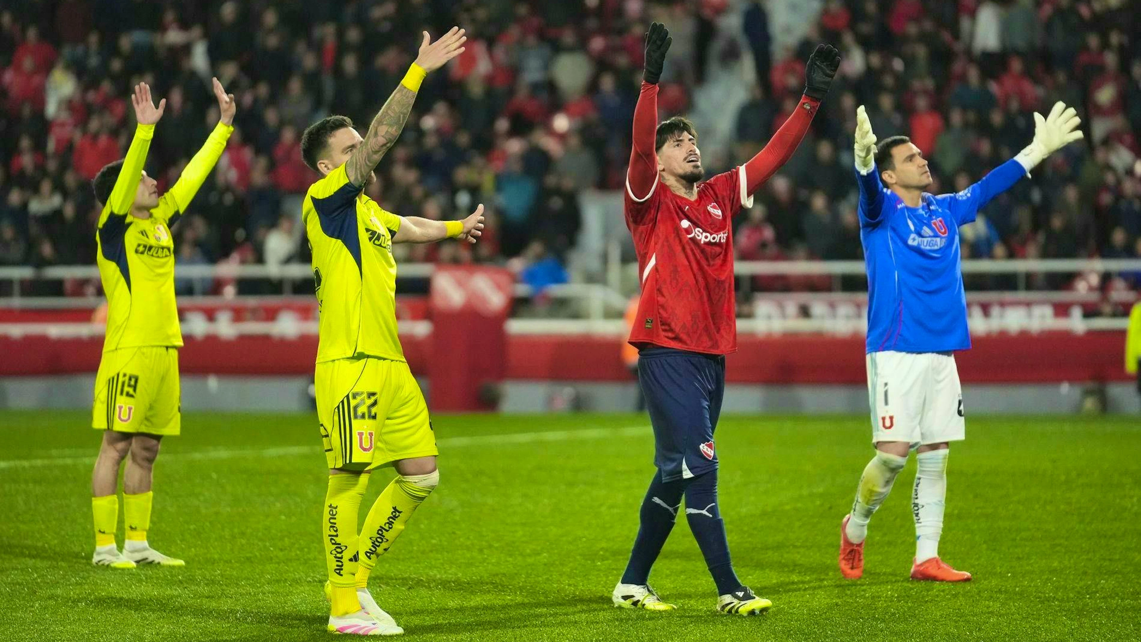 The footballers on the pitch try to calm the spectators.