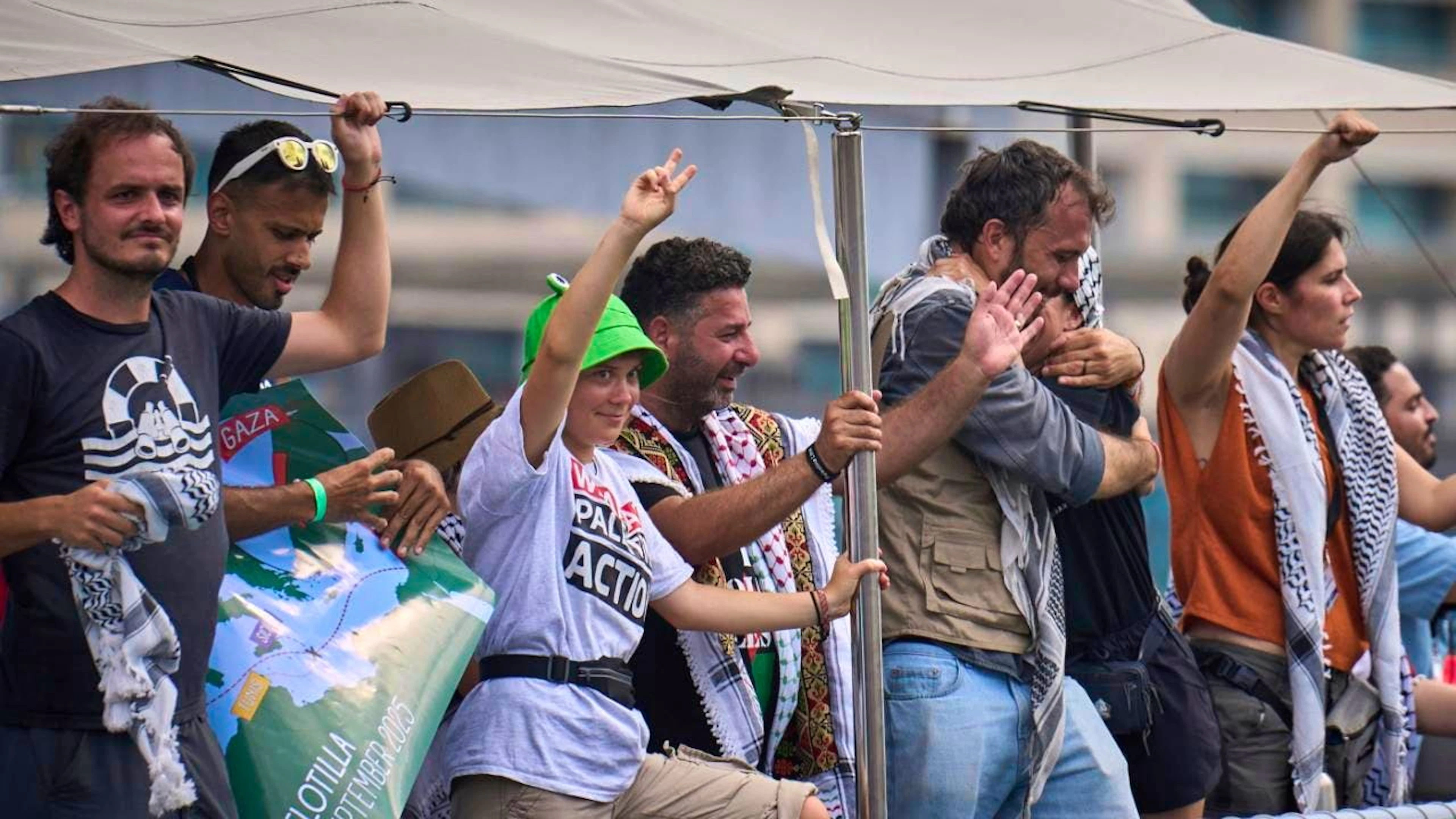 Die schwedische Klimaaktivistin Greta Thunberg (M) winkt von einem Boot aus, das an der Global Sumud Flotilla nach Gaza teilnimmt, um die israelische Blockade zu durchbrechen und humanitäre Hilfe zu leisten. Foto: Emilio Morenatti/AP/dpa