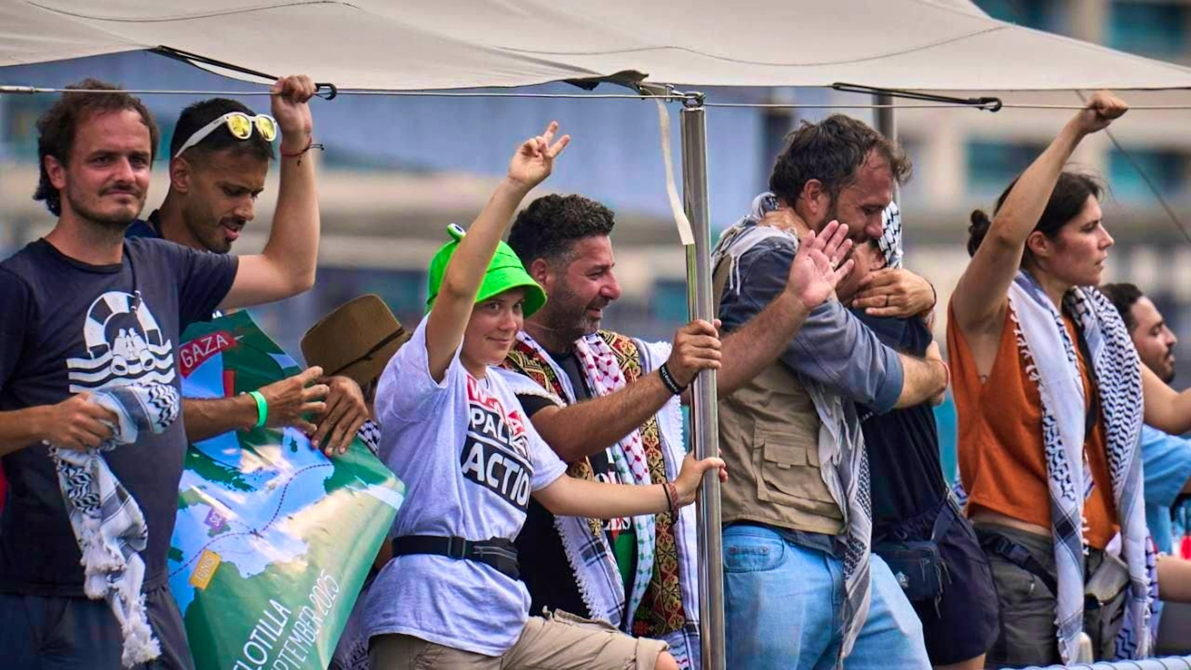 L'attivista svedese per il clima Greta Thunberg (al centro) saluta da una barca che partecipa alla Global Sumud Flotilla diretta a Gaza per rompere il blocco israeliano e fornire aiuti umanitari.