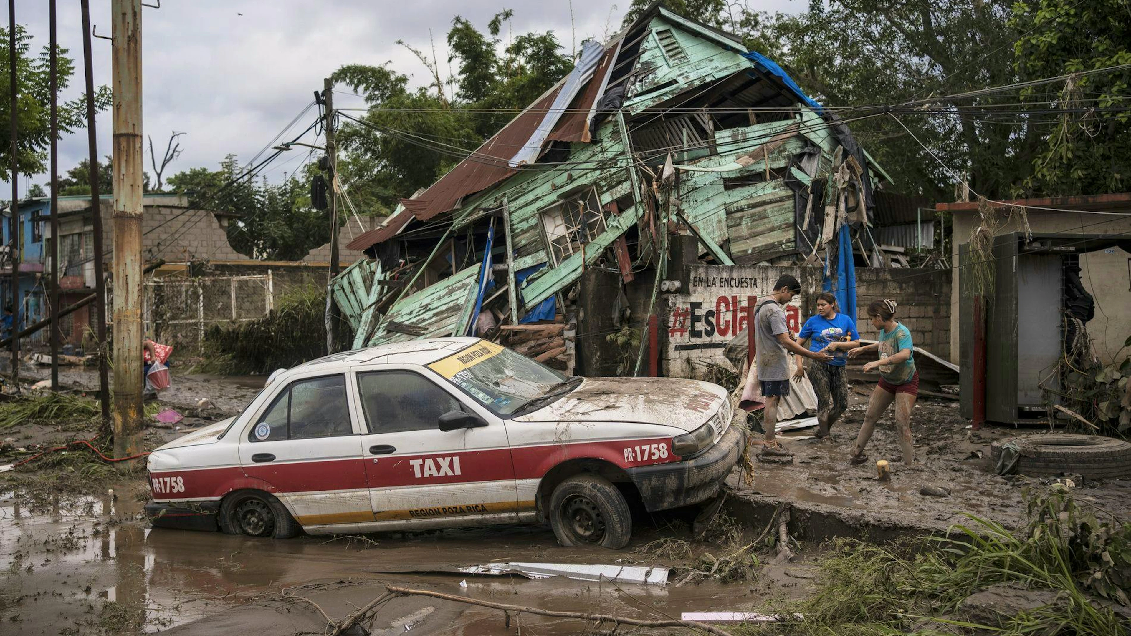 Des voisins se rassemblent autour d'une maison endommagée après de fortes pluies à Poza Rica, dans l'État de Veracruz, au Mexique, le samedi 11 octobre 2025. (AP Photo/Felix Marquez)