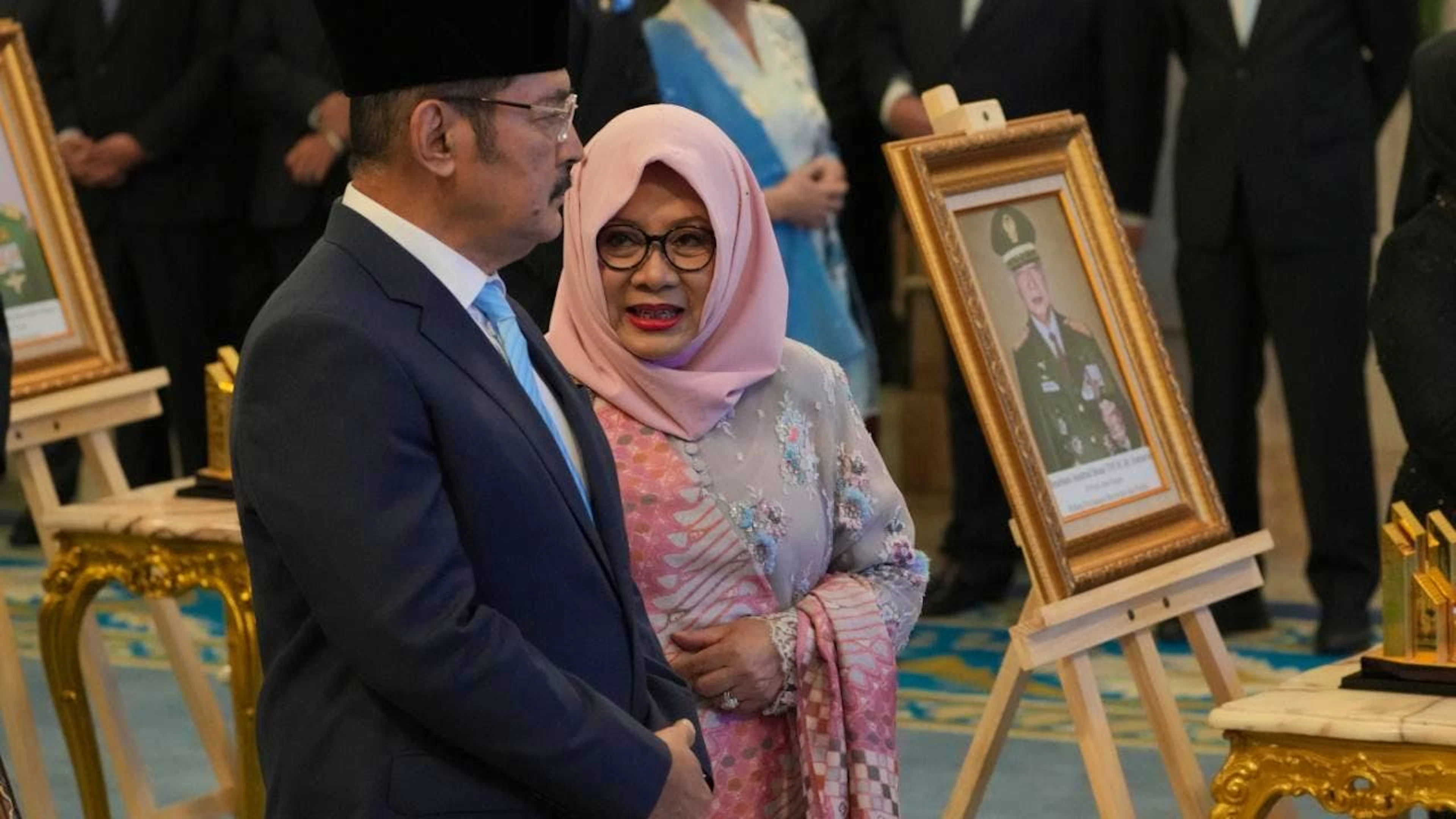 Siti Hardiyanti Rukmana (2.v.l), Tochter des verstorbenen Präsidenten Suharto, und dessen Sohn Bambang Trihatmojo (l) stehen neben dem Porträt ihres Vaters während einer Zeremonie zur Verleihung des Status «Nationalheld» an zehn Persönlichkeiten, darunter der ehemalige indonesische Machthaber, im Staatspalast ausgestellt. Foto: Achmad Ibrahim/AP/dpa