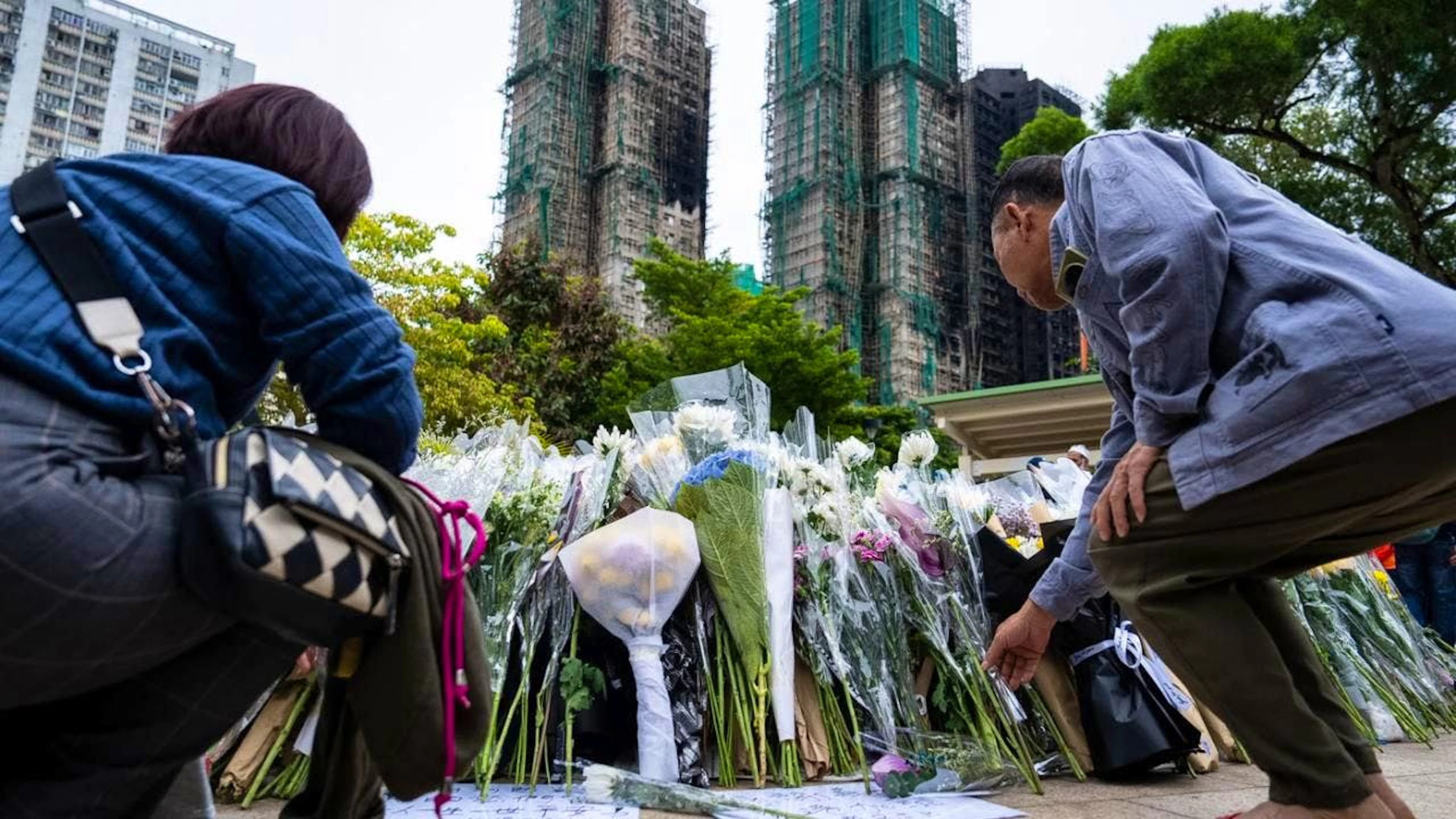 Menschen legen Blumen für die Opfer des tödlichen Brandes im Wang Fuk Court nieder. Foto: Chan Long Hei/AP/dpa