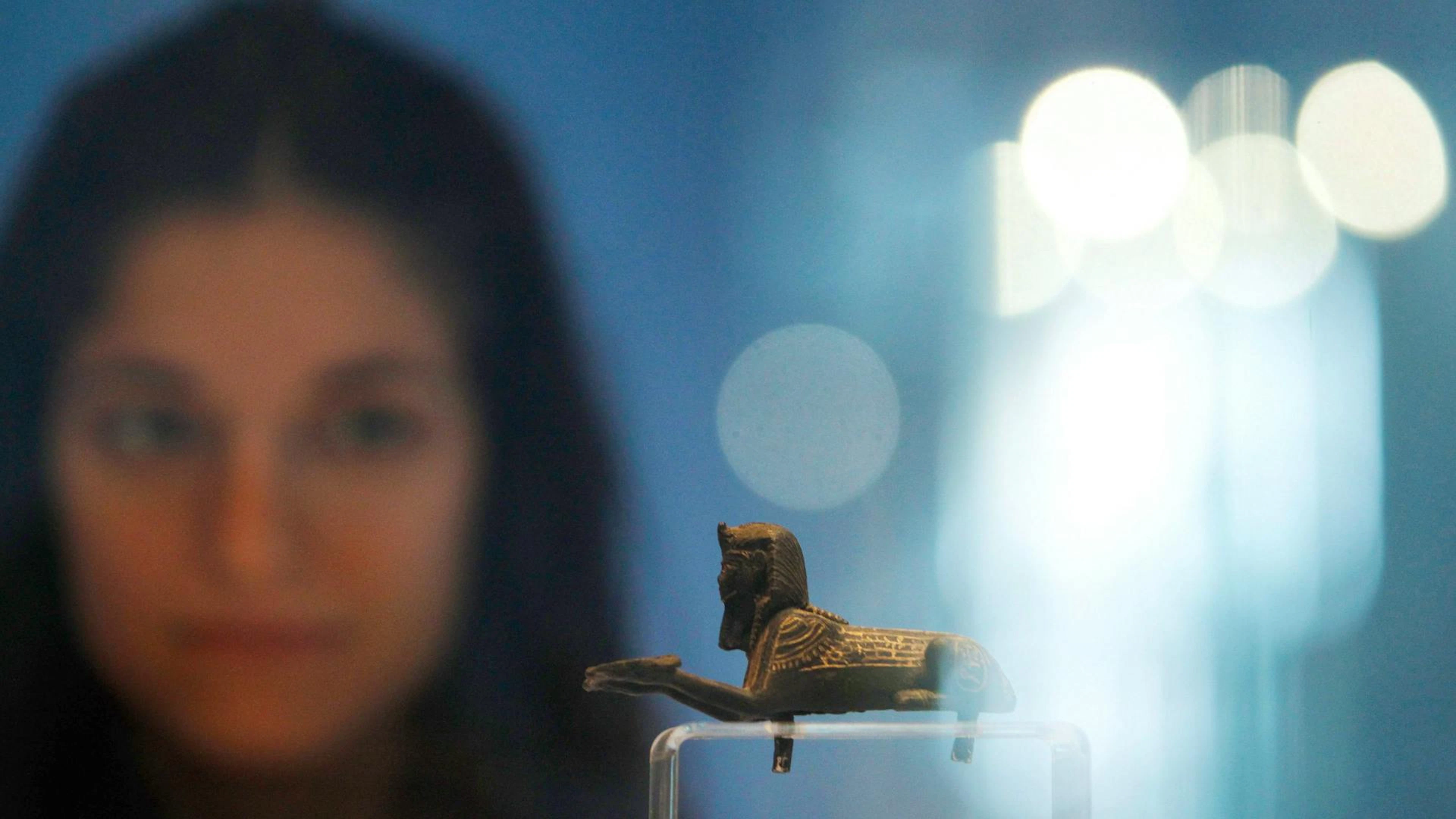 Eine junge Frau betrachtet eine Miniatur-Sphinx aus der königlichen Nekropole von Tanis. Das Kleinod stammt aus einem Königsgrab in Tanis und wurde von Pierre Montet ausgegraben.