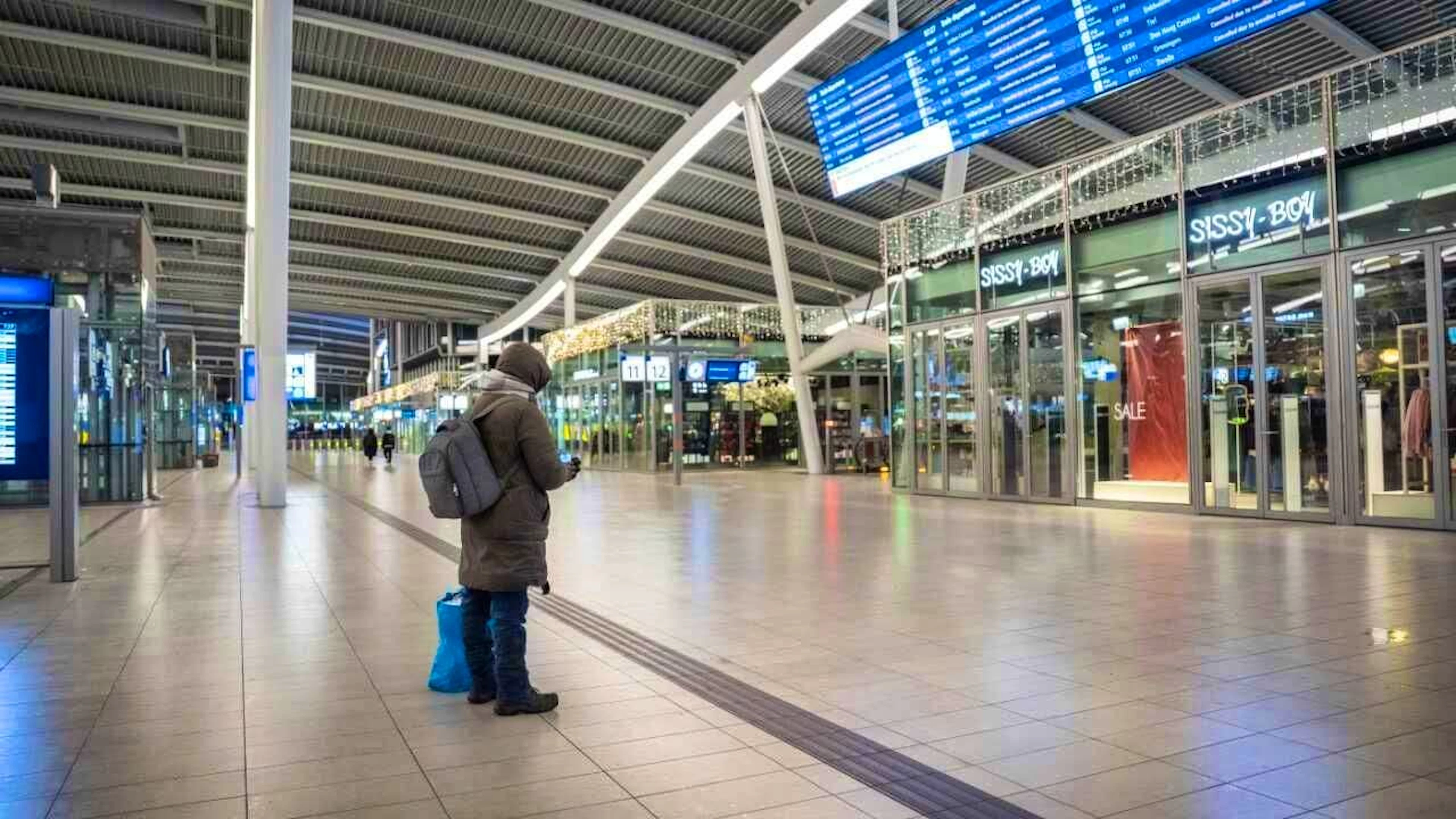 A person stands in front of a display board in the empty hall of Utrecht Central Station. The trains of the Dutch Railways (NS) are currently not running due to winter weather and an IT malfunction. Photo: Jeroen Jumelet/ANP/dpa