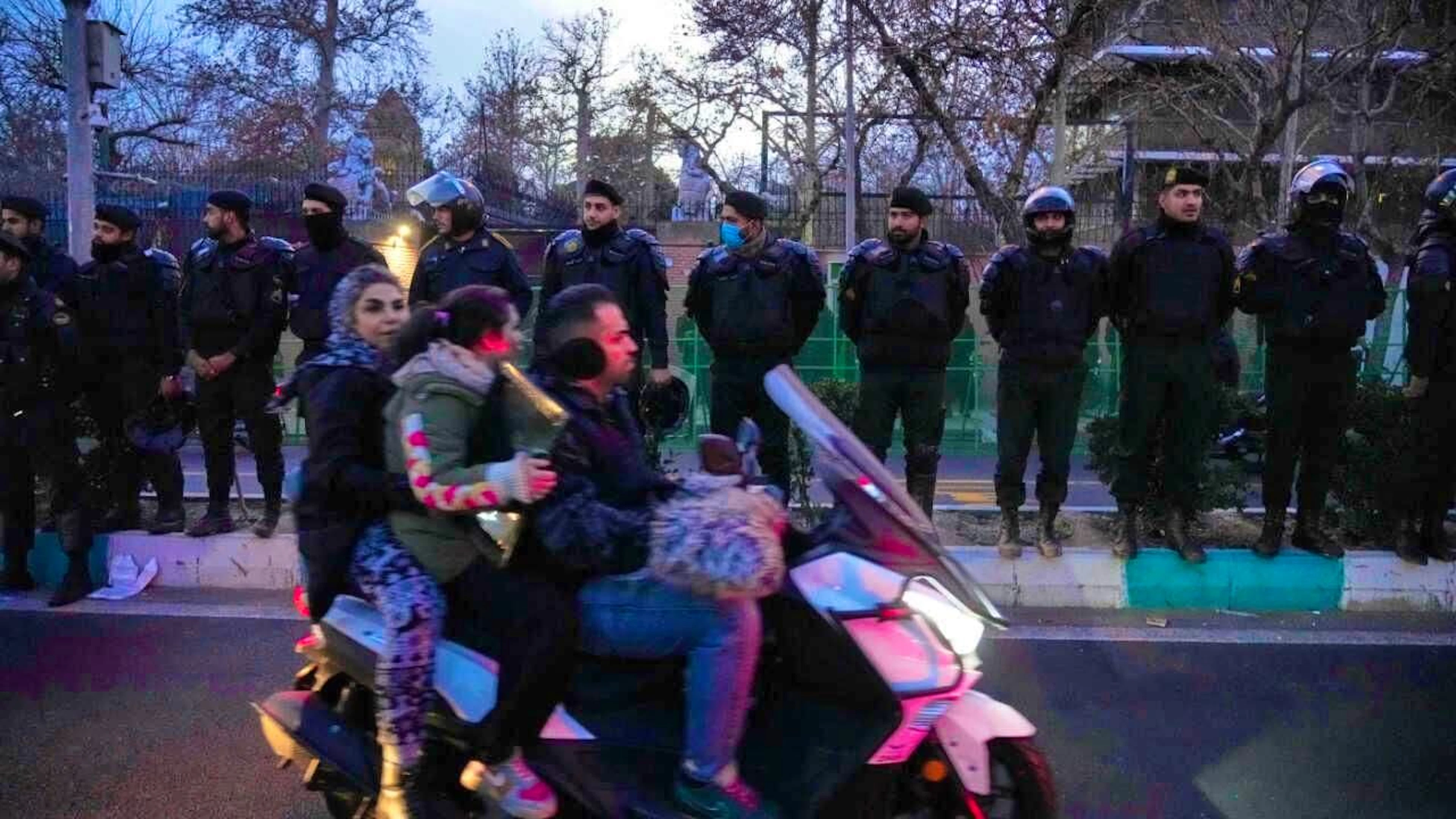 Police officers protect the British embassy during a demonstration by hardline supporters of the Iranian government, while people ride past the police on their motorcycles. Photo: Vahid Salemi/AP/dpa