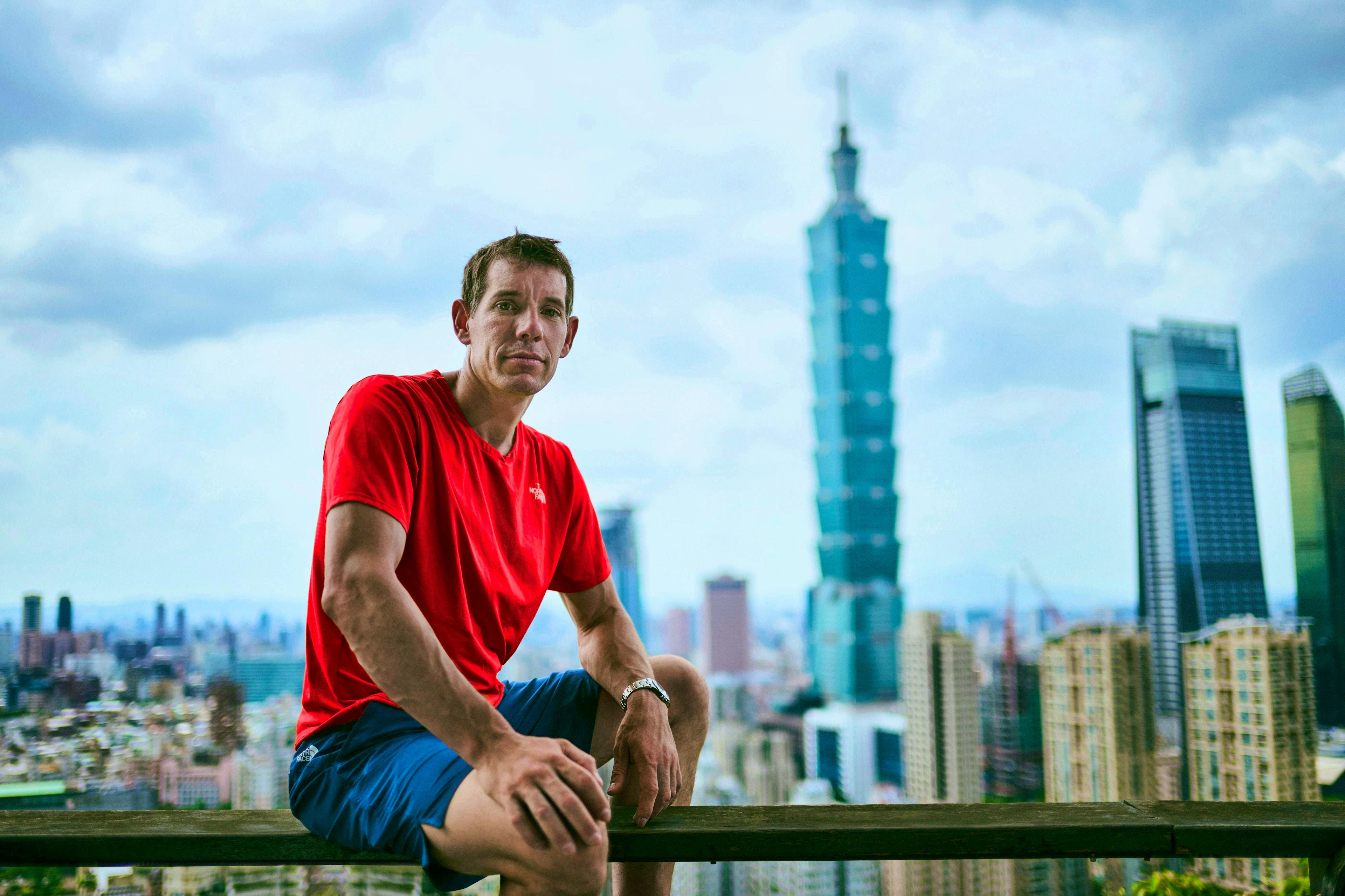 Alex Honnold a Taipei, Taiwan. Sullo sfondo il grattacielo che scalerà il 23 gennaio.