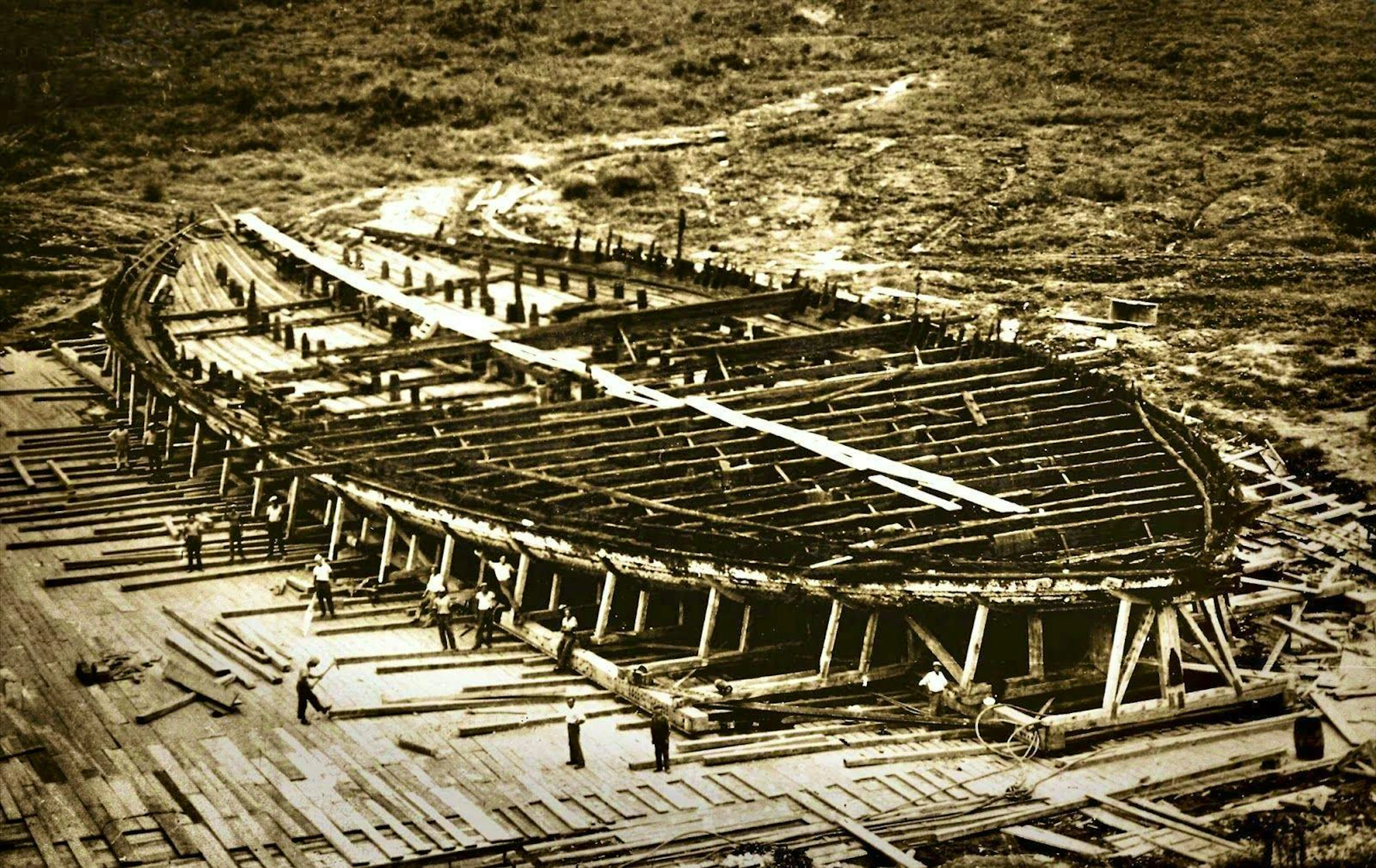L'enorme scafo di una nave di Nemi è esposto dopo l'affondamento del lago. Gli operai mettono in sicurezza l'antica costruzione (1928).