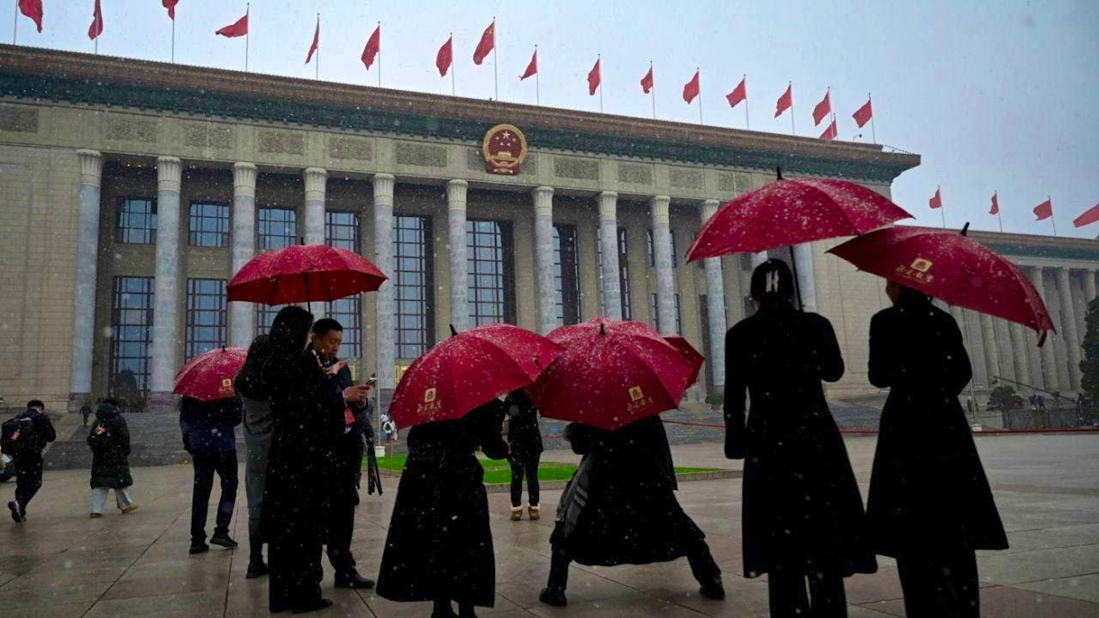 dpatopbilder - People walk under snowfall to the Great Hall of the People. Photo: Johannes Neudecker/dpa