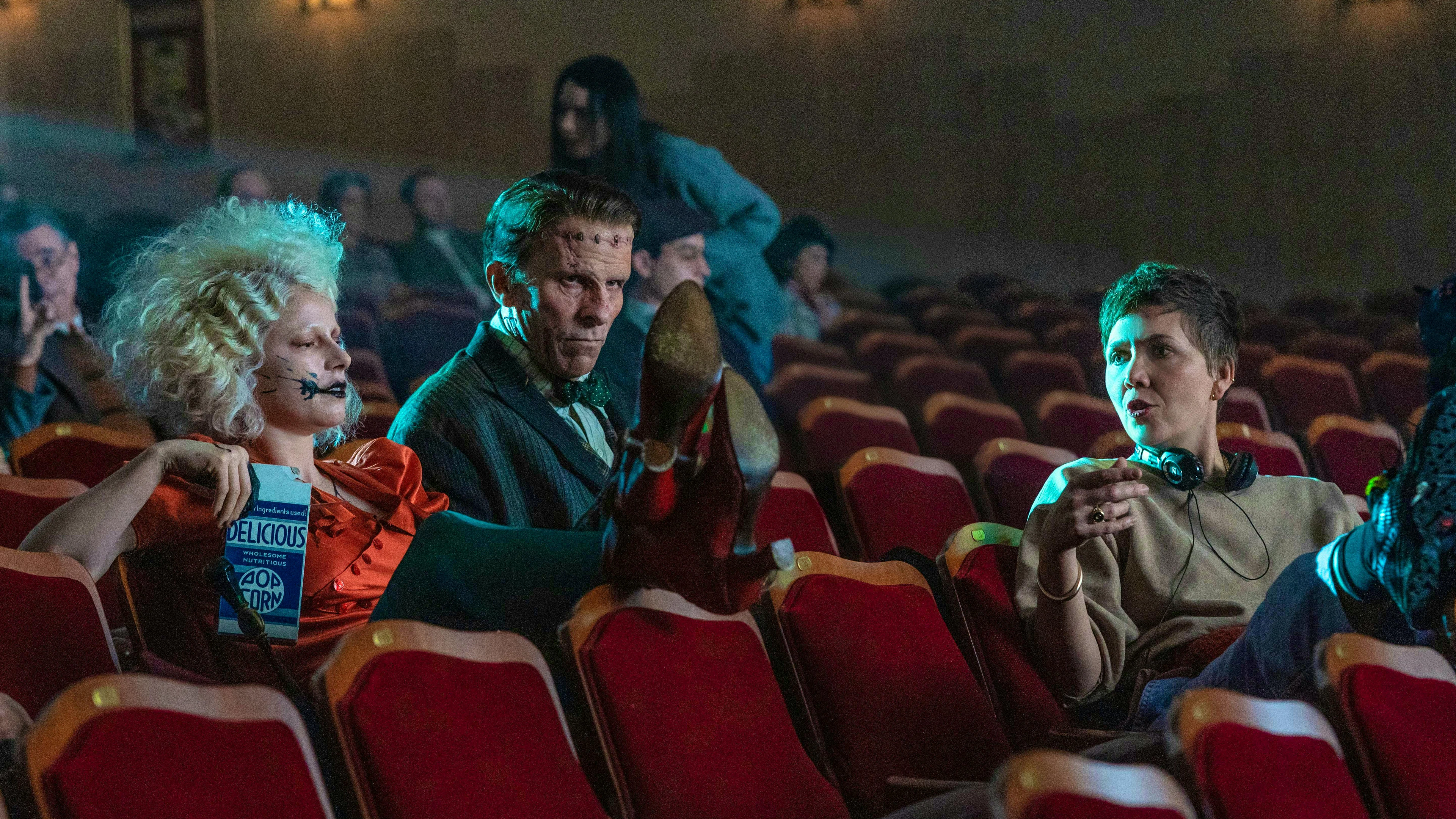 Director Maggie Gyllenhaal with her monsters while filming in a movie theater.