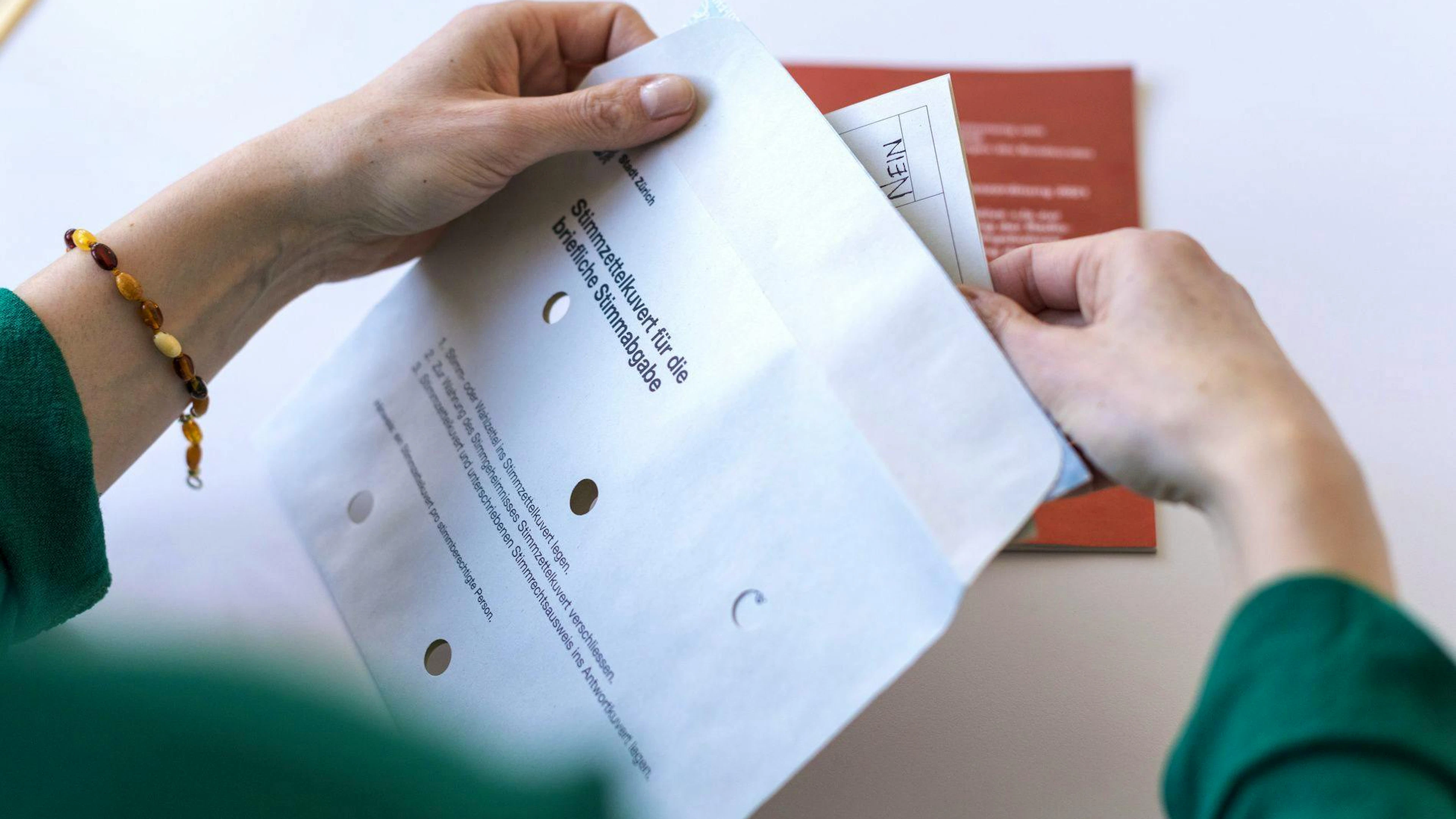 Die Stimmzettel gehören ins Couvert mit den Löchern. Dieses Stimmcouvert muss zugeklebt werden und zusammen mit dem unterschriebenen Stimmausweis ins Rücksendecouvert gesteckt werden.