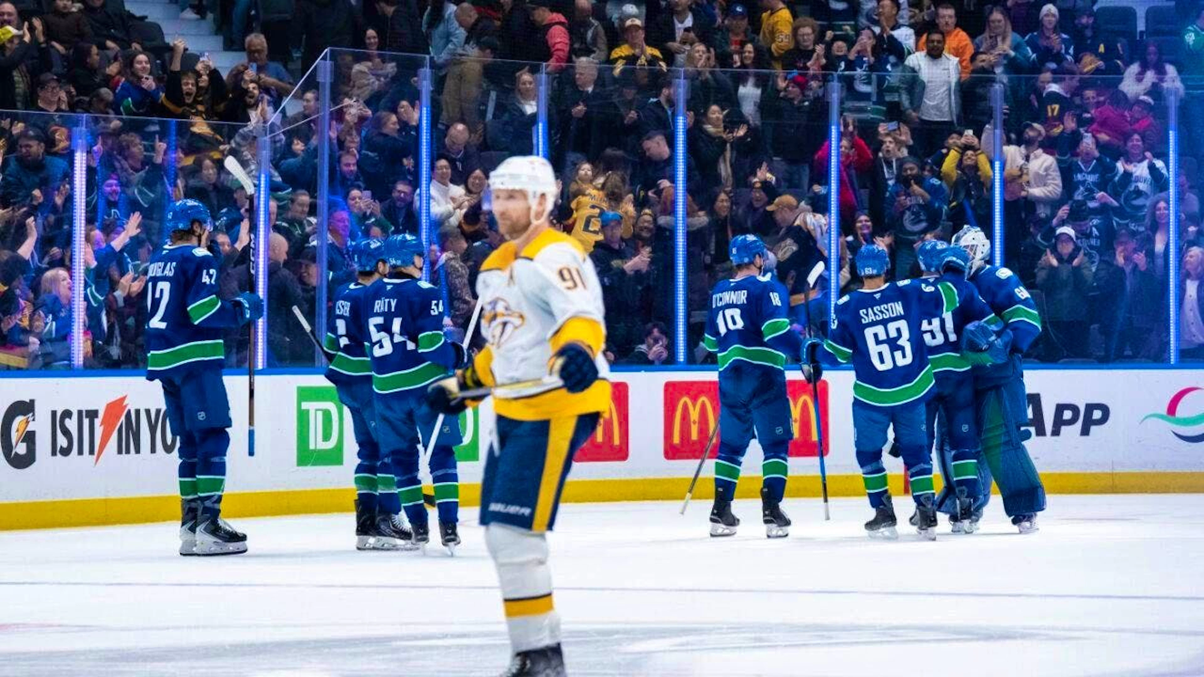 While the Vancouver players celebrate the win, Nashville's Steven Stamkos heads to the visitors' bench in disappointment