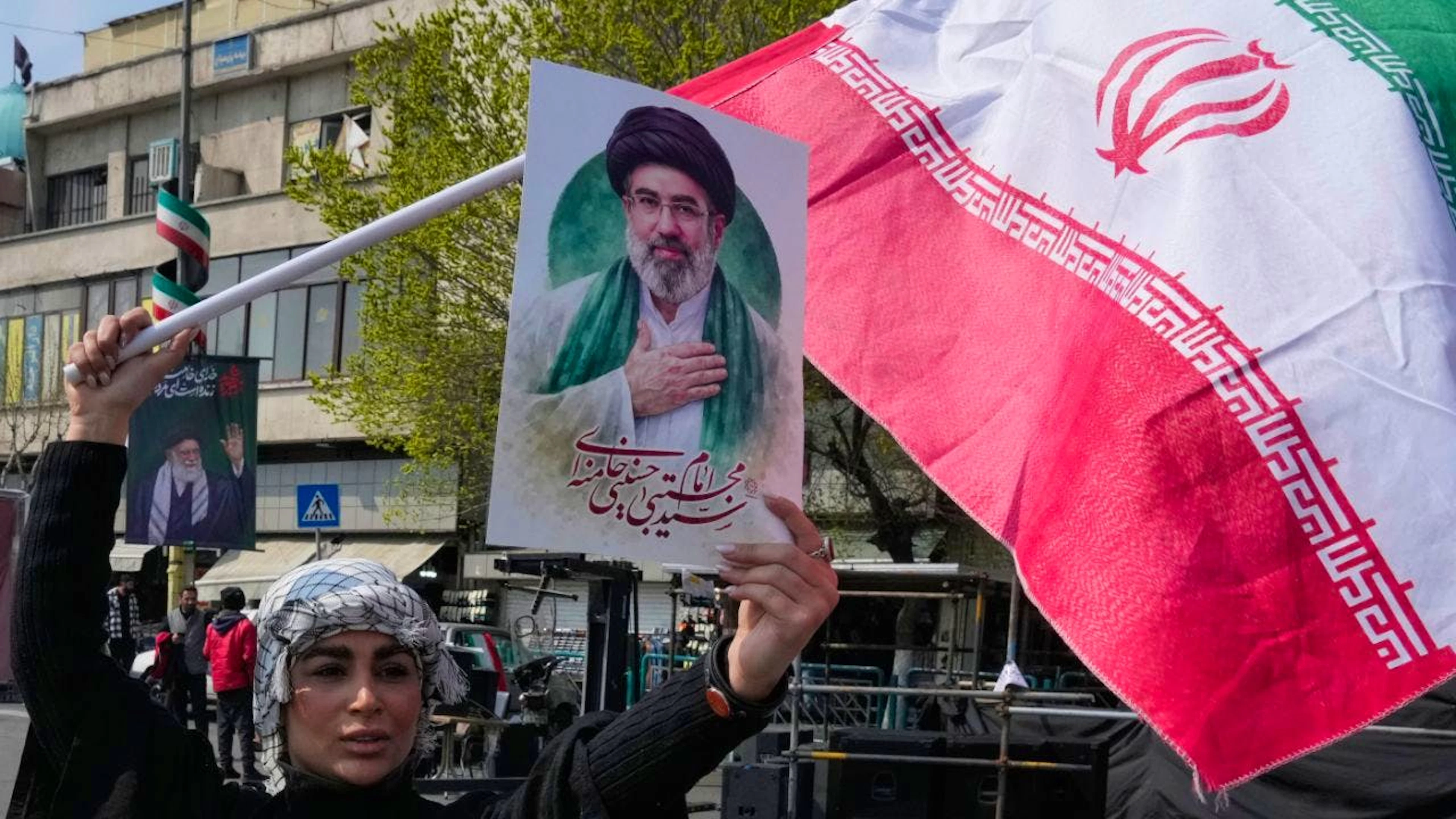 Una donna sventola un poster dell'Ayatollah Mojtaba Khamenei a Teheran.
