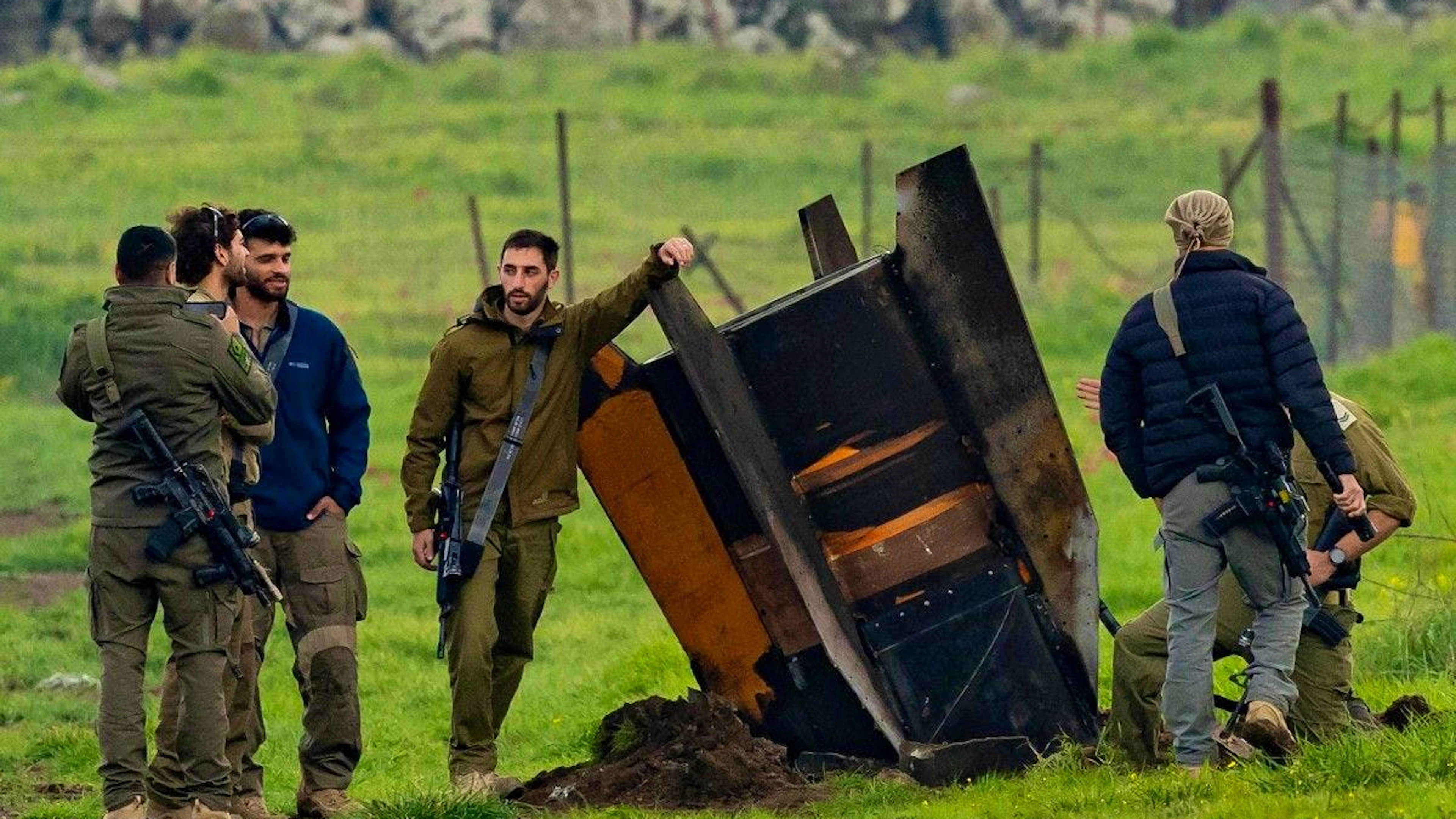 Des membres des forces de sécurité israéliennes sécurisent le périmètre autour d’une roquette partiellement enfouie dans un champ, sur le plateau du Golan (territoire annexé par Israël et situé à la frontière avec le Liban), le 19 mars 2026.