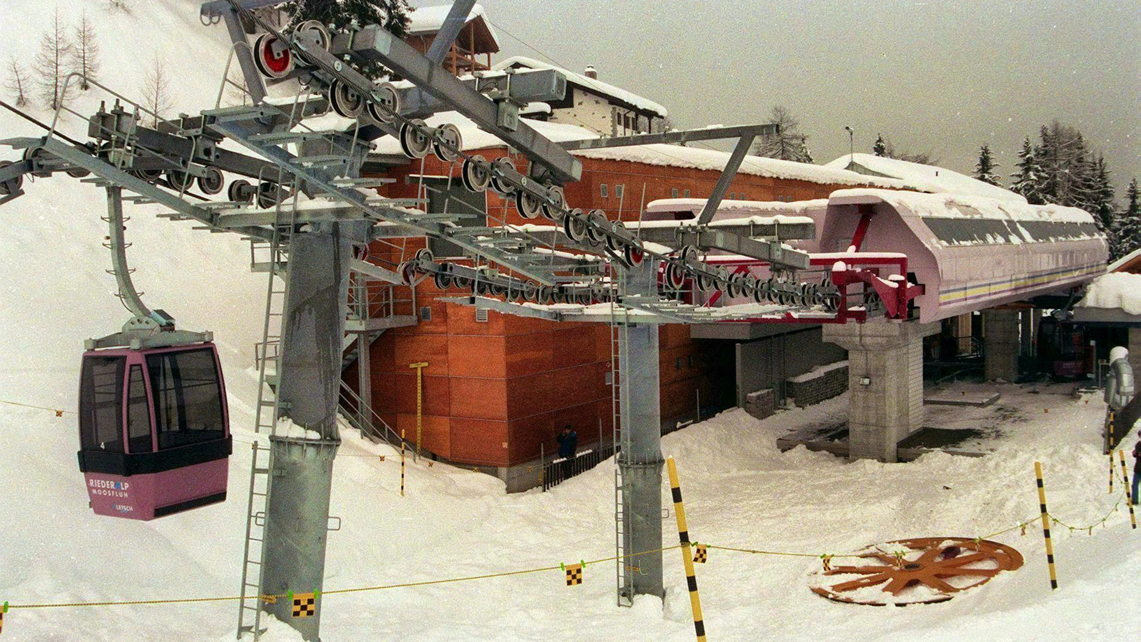 The orange sheave, over which the only cable of the Riederalp Railway runs, lies in the snow in front of the station building. It was torn from its anchoring when the axle broke.
