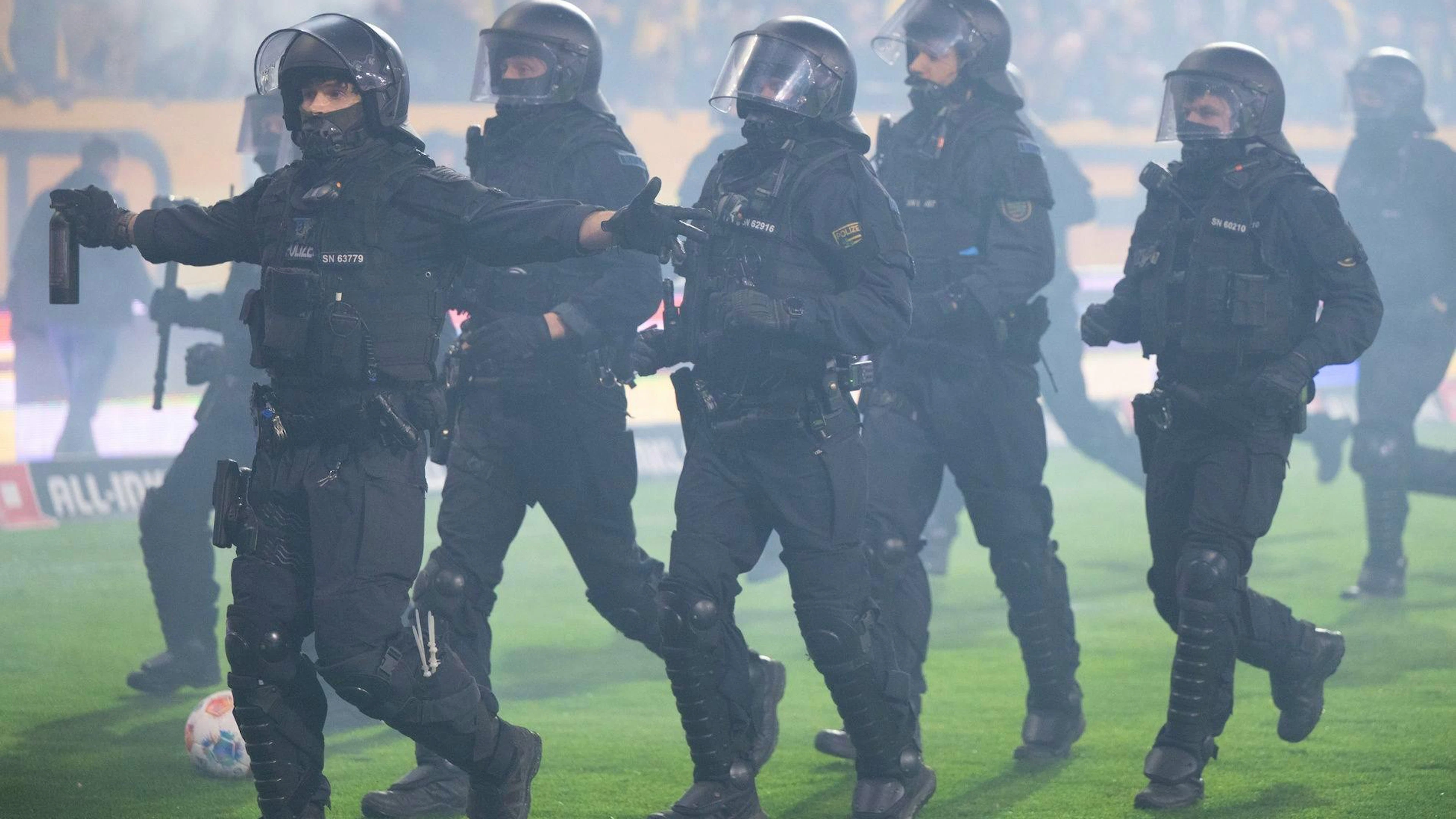 Polizisten stehen während der Spielunterbrechung im Stadion vor dem Gästeblock.