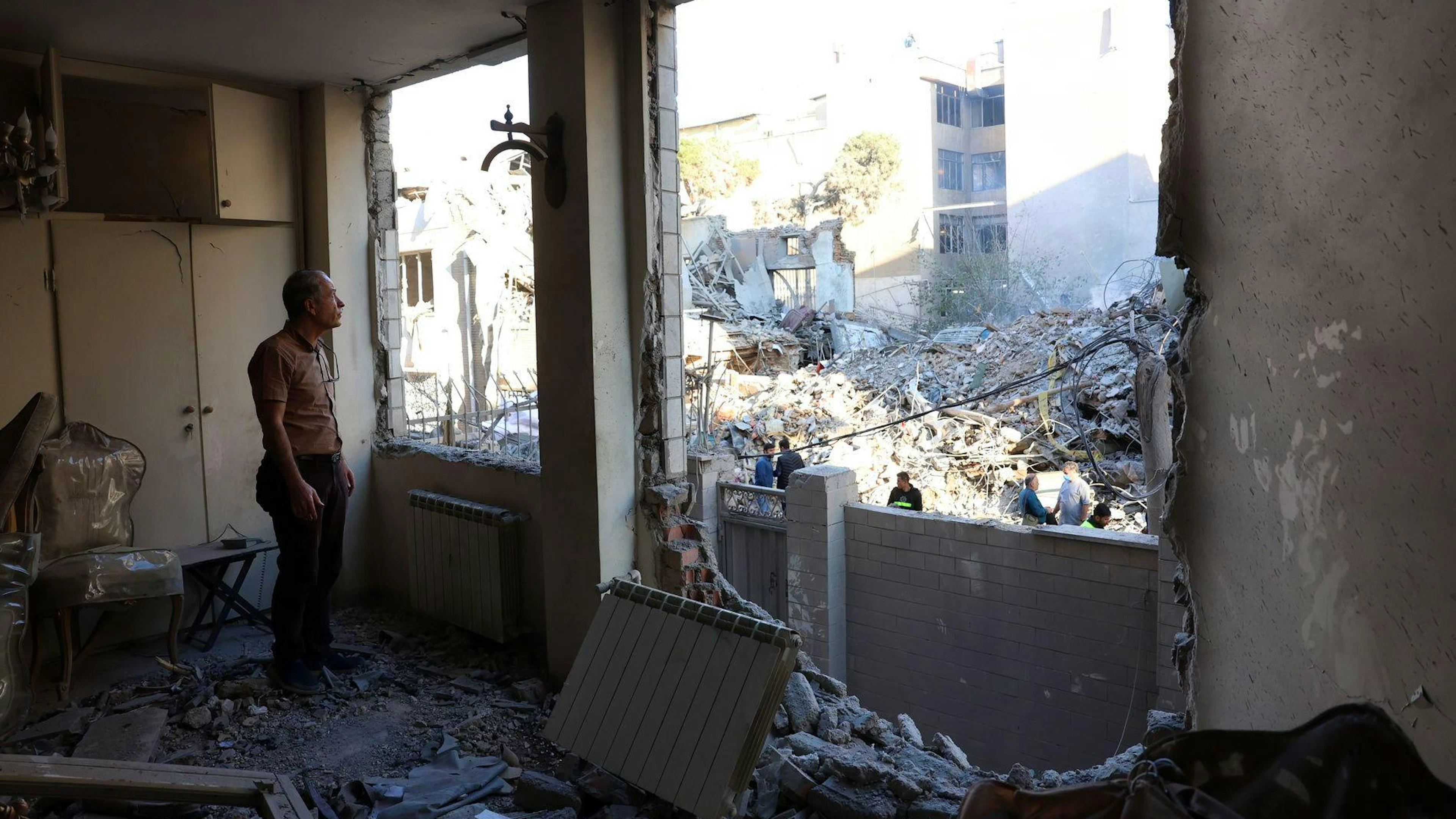 Ein iranischer Zivilist blickt am Dienstag (7.4.) aus seinem zerstörten Wohnblock neben der ebenfalls zerstörten Khorasaniha Synagoge in Teheran.