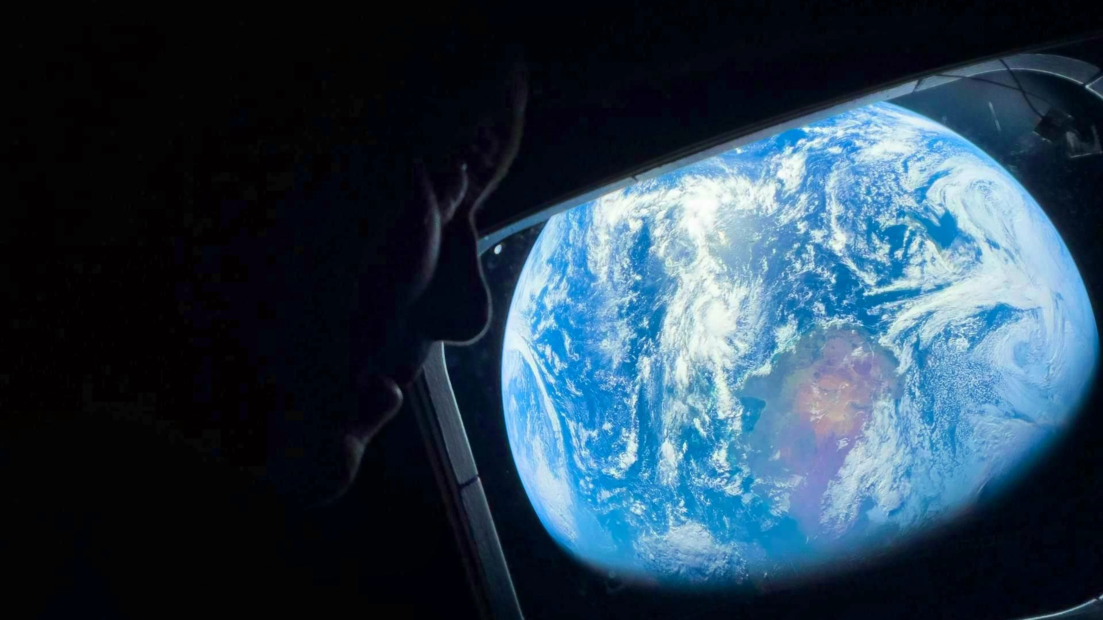Commander Reid Wiseman looks back at Earth from one of the Orion capsule's main windows as the spacecraft is on its way to the moon.