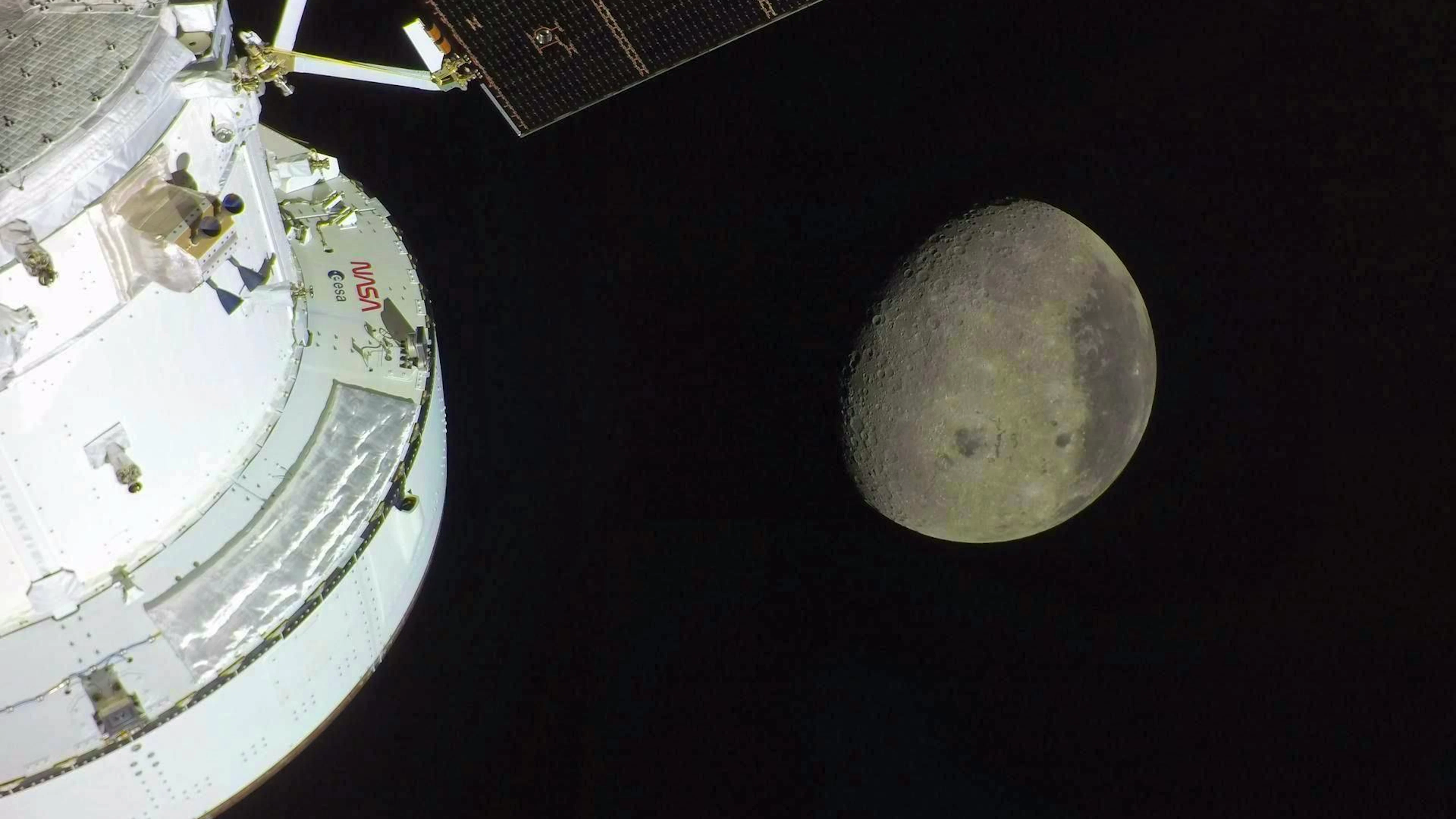 The spacecraft "Orion" can be seen in the foreground, illuminated by the sun. A waxing moon can be seen in the background. The Orientale Basin, an impact crater about 1000 kilometers wide and surrounded by mountains, can be seen in the lower half of the moon.