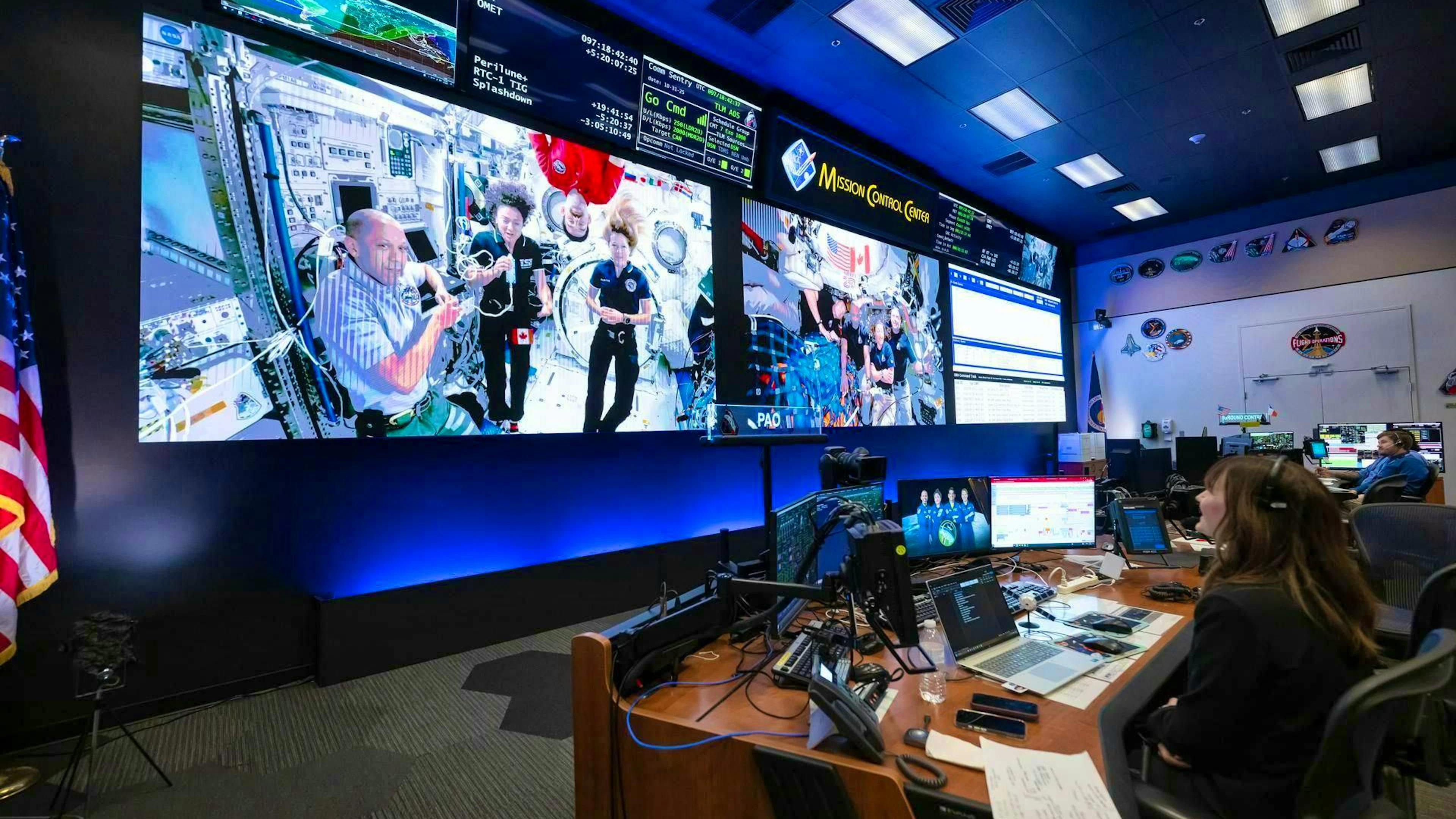 On the screens in the flight control room of the International Space Station at NASA's Johnson Space Center in Houston, members of the crews of the International Space Station Expedition 74 (left) and Artemis II (right) can be seen simultaneously. The two crews had a 15-minute spaceship-to-spaceship conversation on April 7, 2026, while the Artemis II crew was on its way back from the moon.