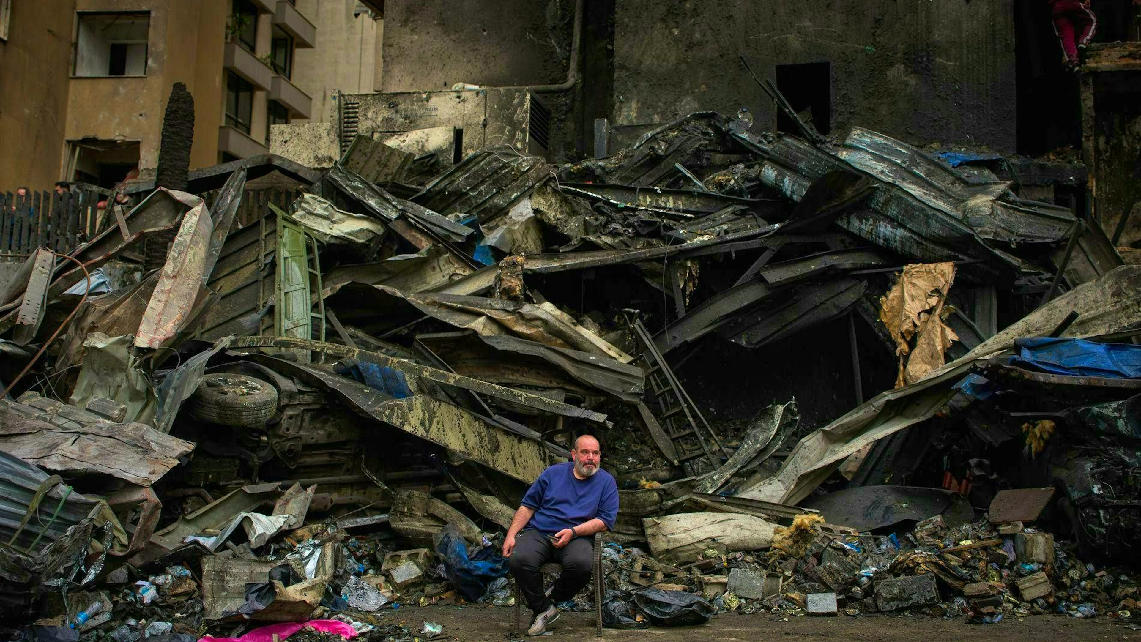 A man sits in front of the charred rubble of a building destroyed in an Israeli airstrike in Beirut (April 10, 2026.