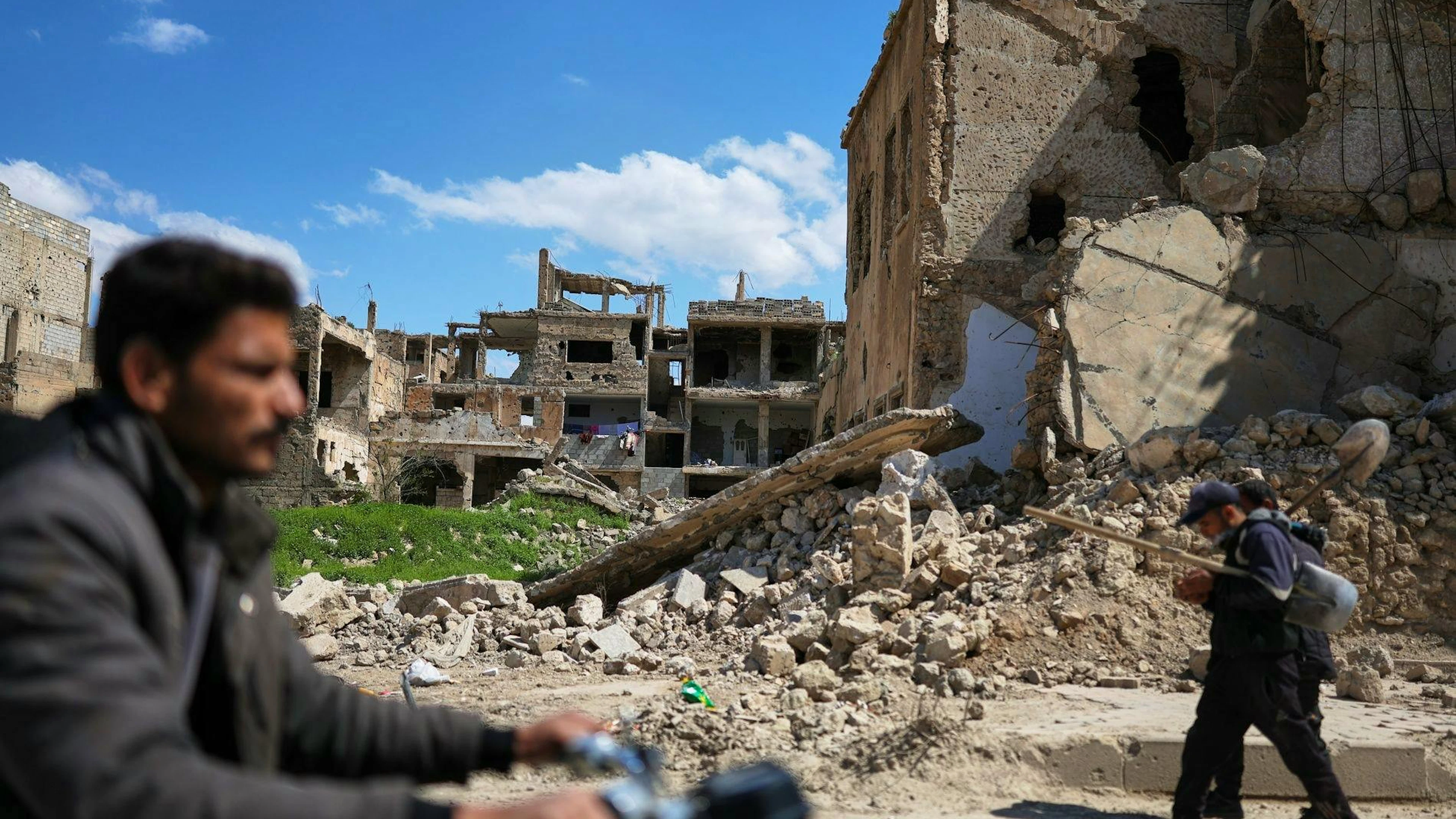 Des habitants passent devant les ruines d’immeubles détruits pendant la guerre à Deir ez-Zor, dans le nord-est de la Syrie, le 11 avril 2026.