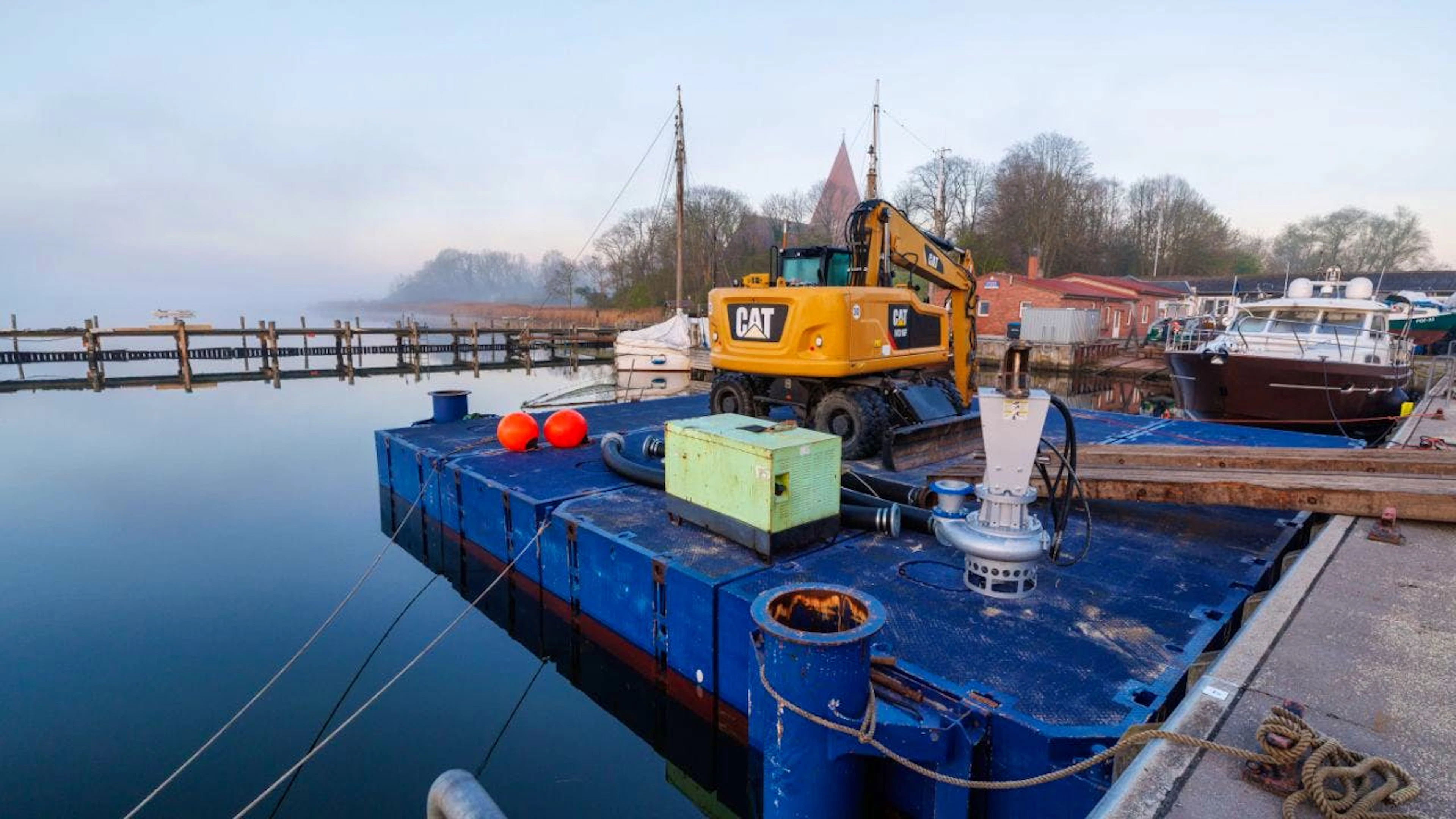 Ein Bagger steht am Morgen auf einem Ponton und soll später bei der Rettung des Buckelwals vor der Ostseeinsel Poel eingesetzt werden. Für den vor der Insel Poel gestrandeten Buckelwal hat ein neuer Rettungsversuch begonnen. Umgesetzt wird das Konzept von einer privaten Initiative. Foto: Jens Büttner/dpa